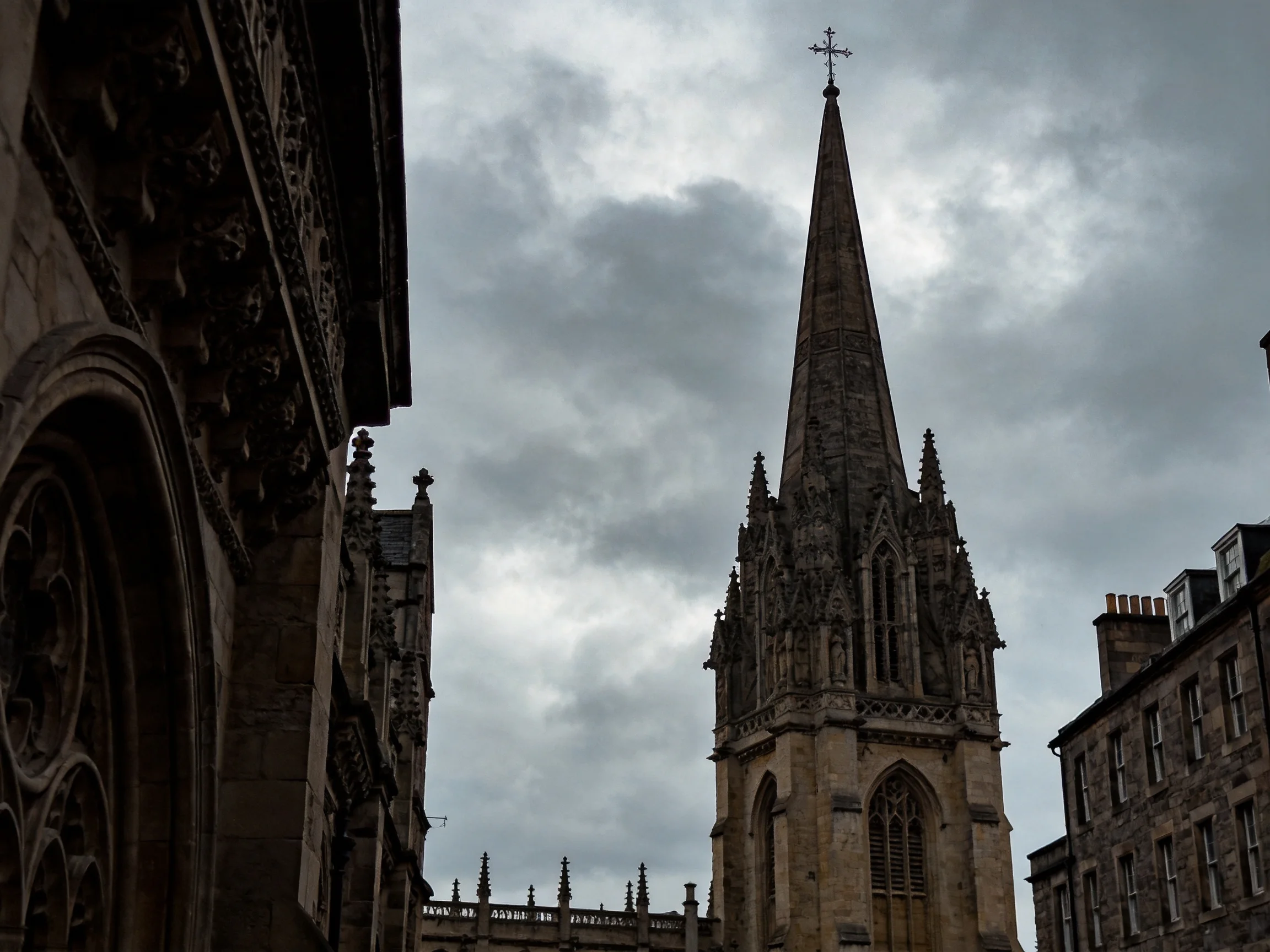 A Gothic Church Tower Among Historic Stone Buildings Under Overcast Sky