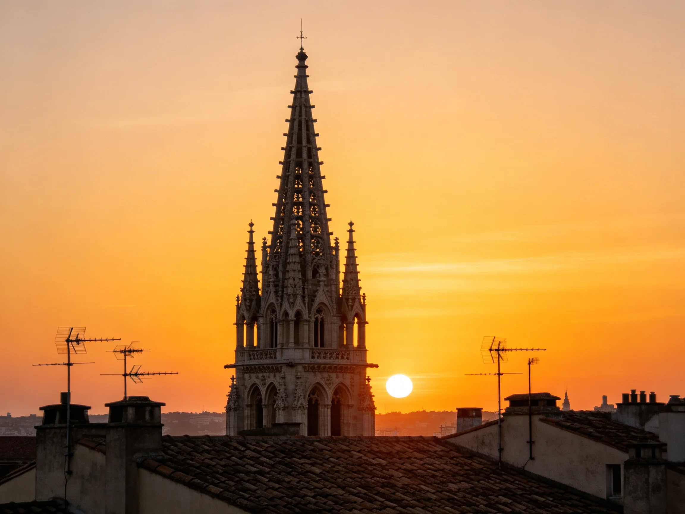 A Gothic Tower Silhouetted Against a Warm Orange Sunset Sky