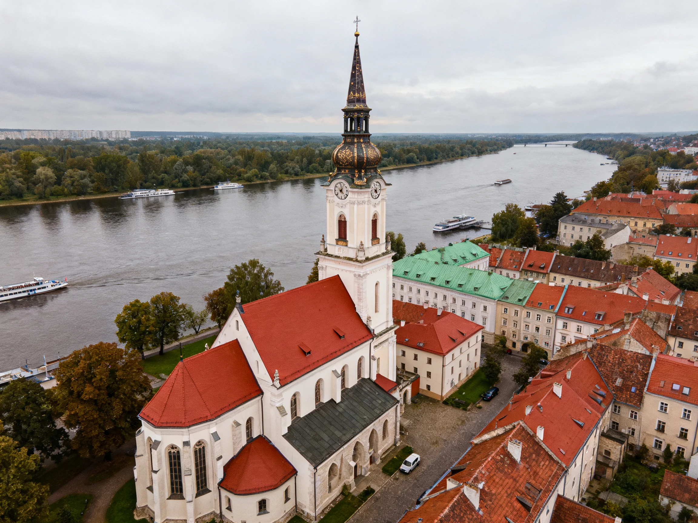 A Historic Church with Red Roofs Overlooks a Winding River