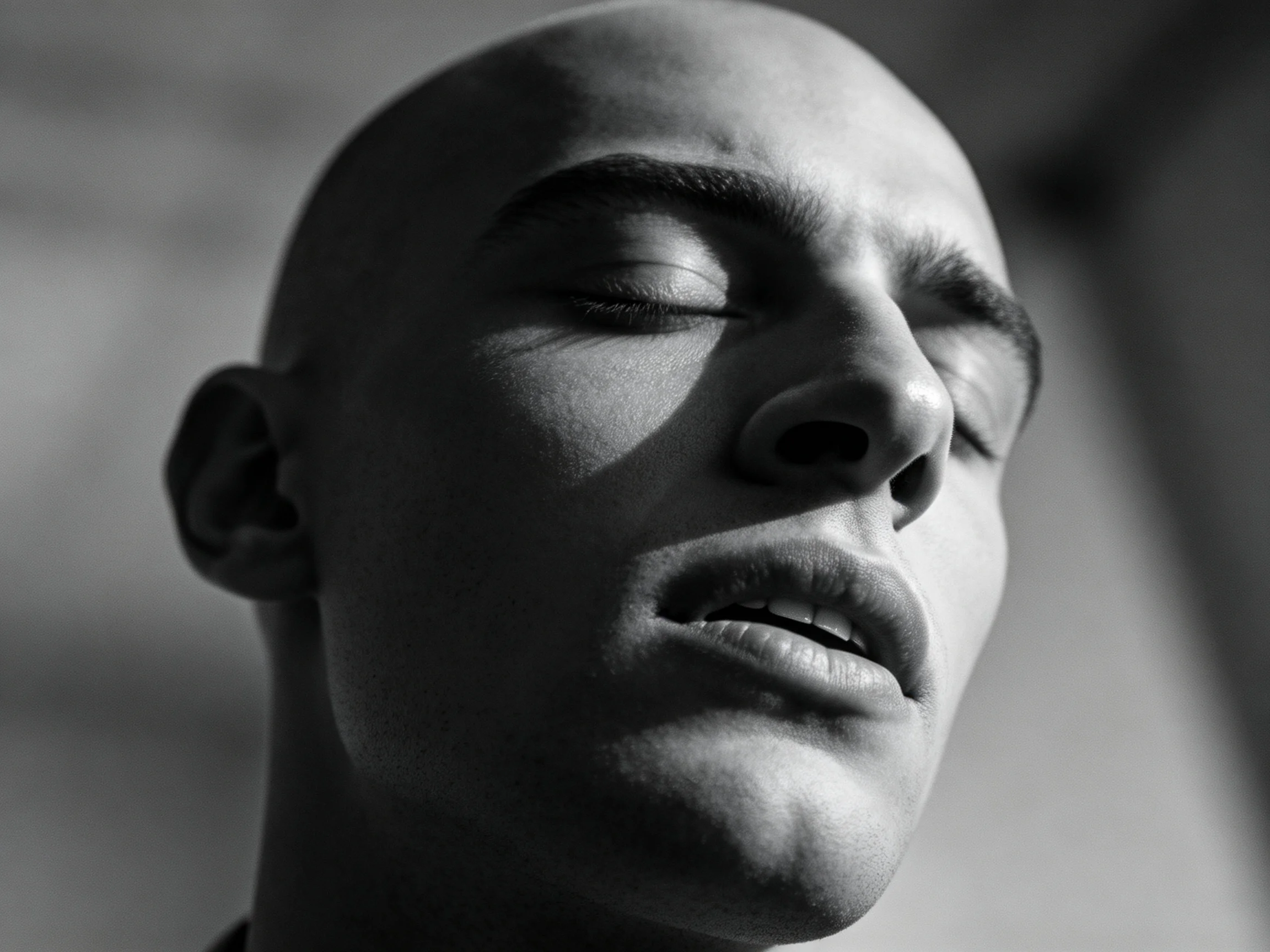 A close - up of a bald individual with dramatic lighting highlighting facial contours