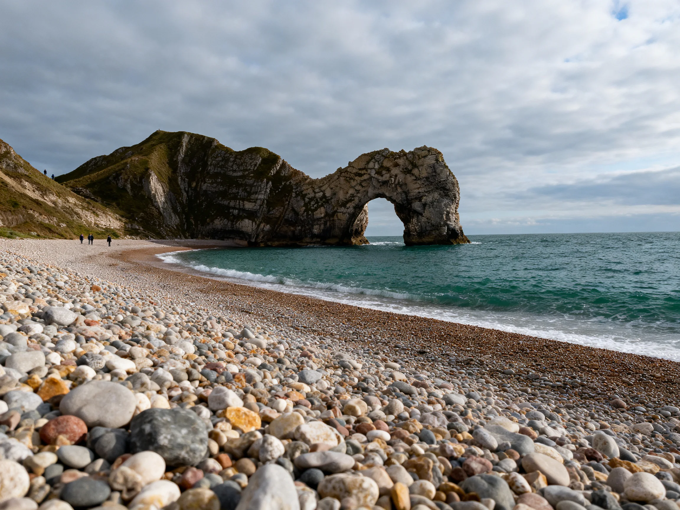A dramatic coastal arch over a pebbly beach with turquoise waters
