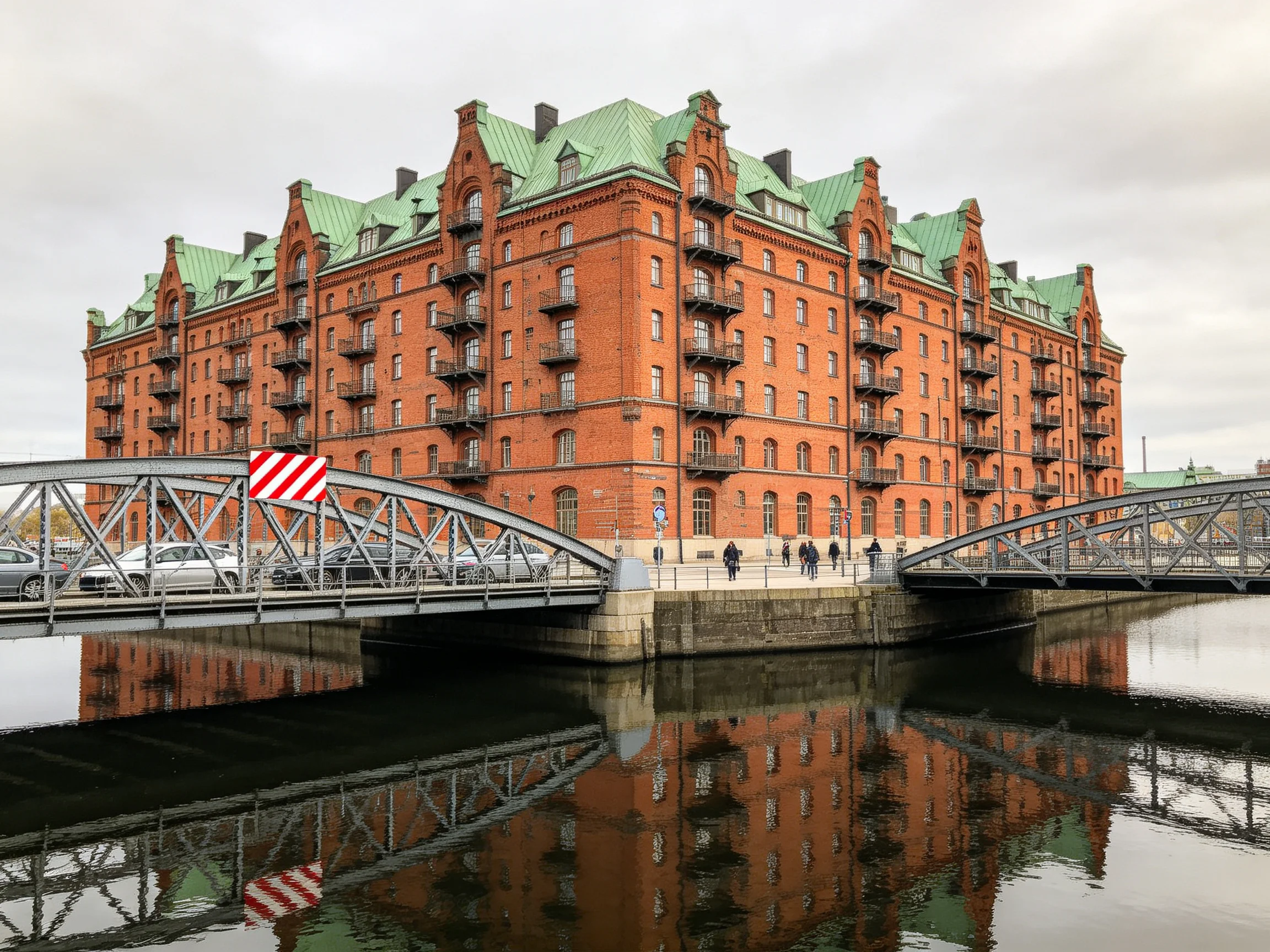A grand red-brick building with green roof near waterways