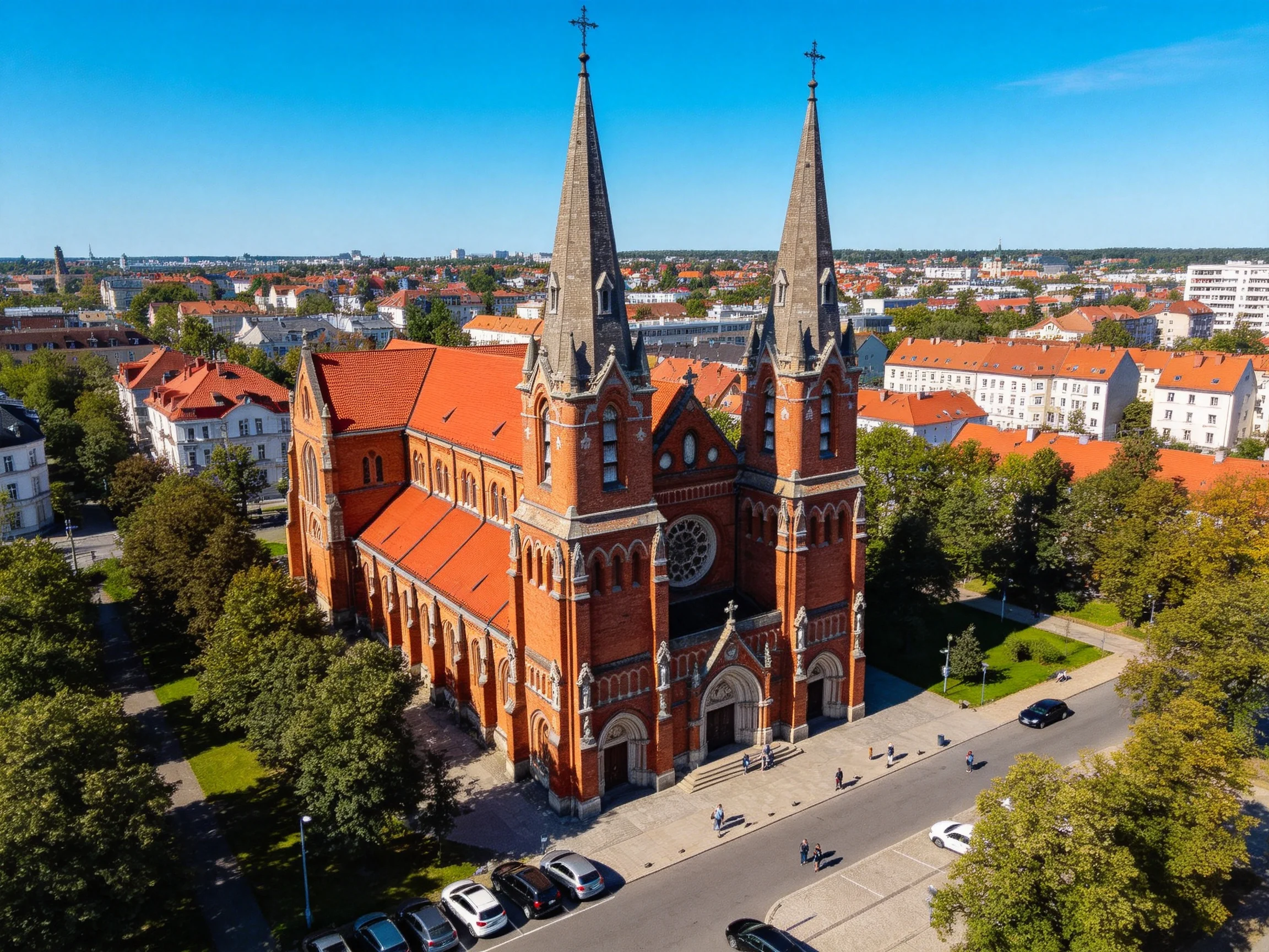 A grand red-brick church with twin spires in an urban setting