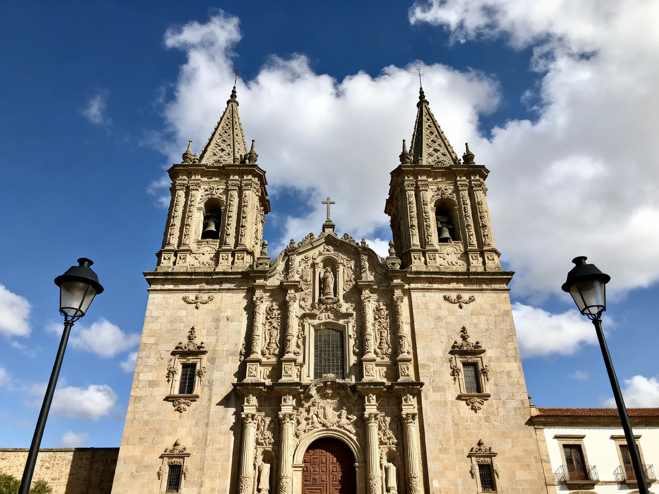 A grand stone church with twin ornate towers under a bright blue sky