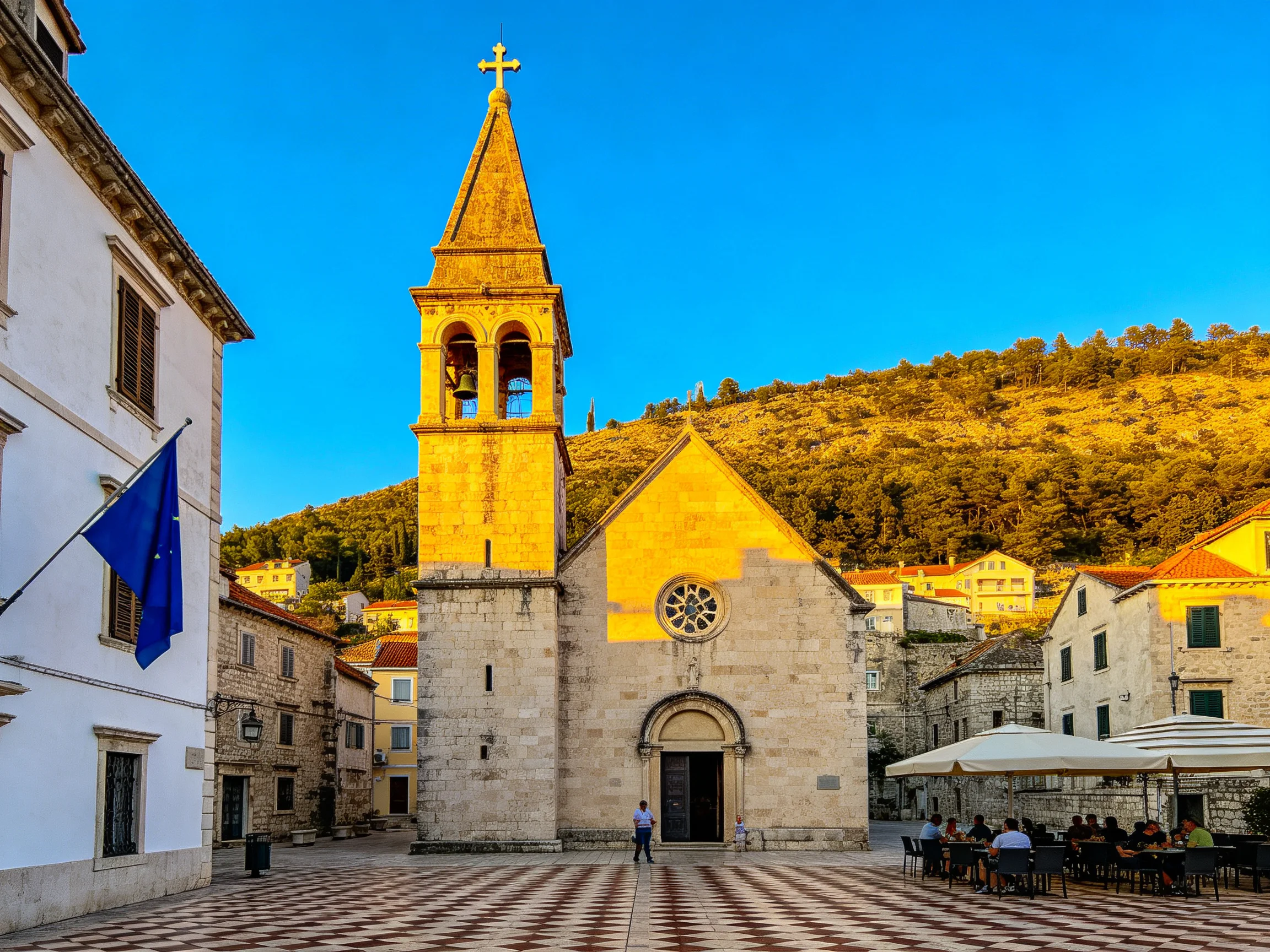 A historic church with a tall bell tower in a cobblestone square