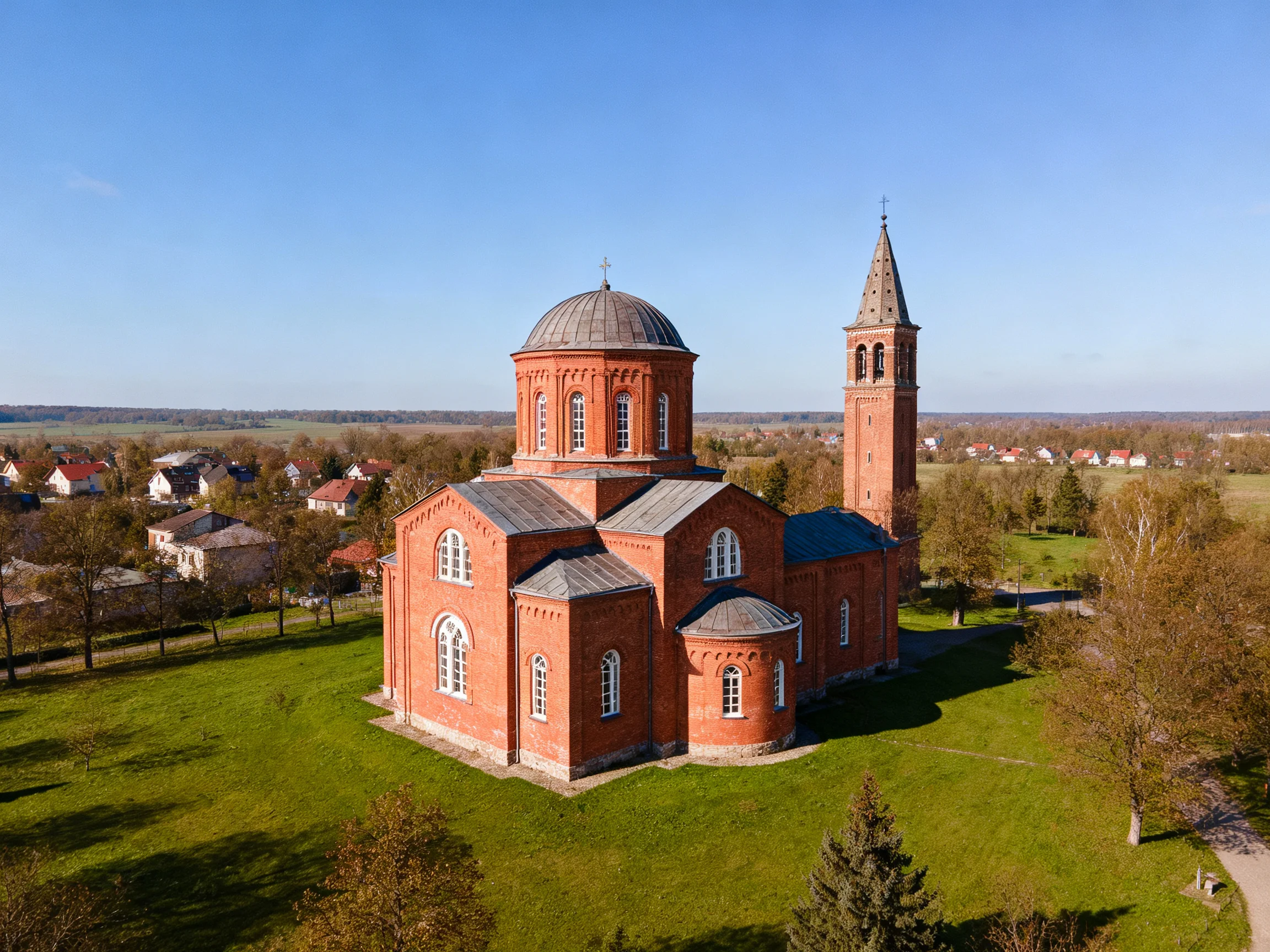 A historic red-brick church with a tall bell tower near residential homes