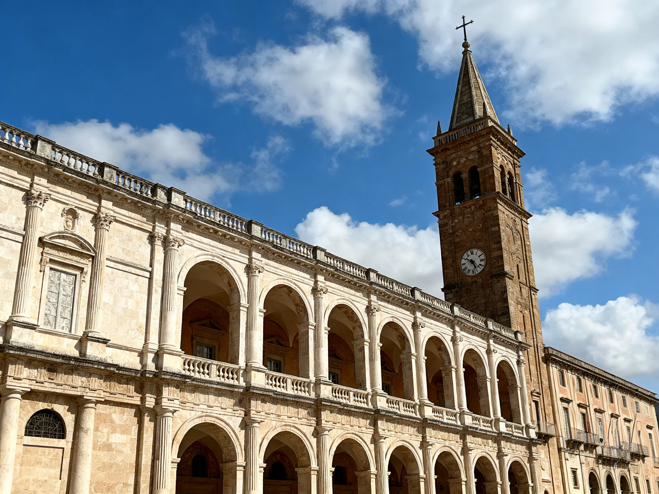 A historic stone building with arched colonnades and a tall clock tower