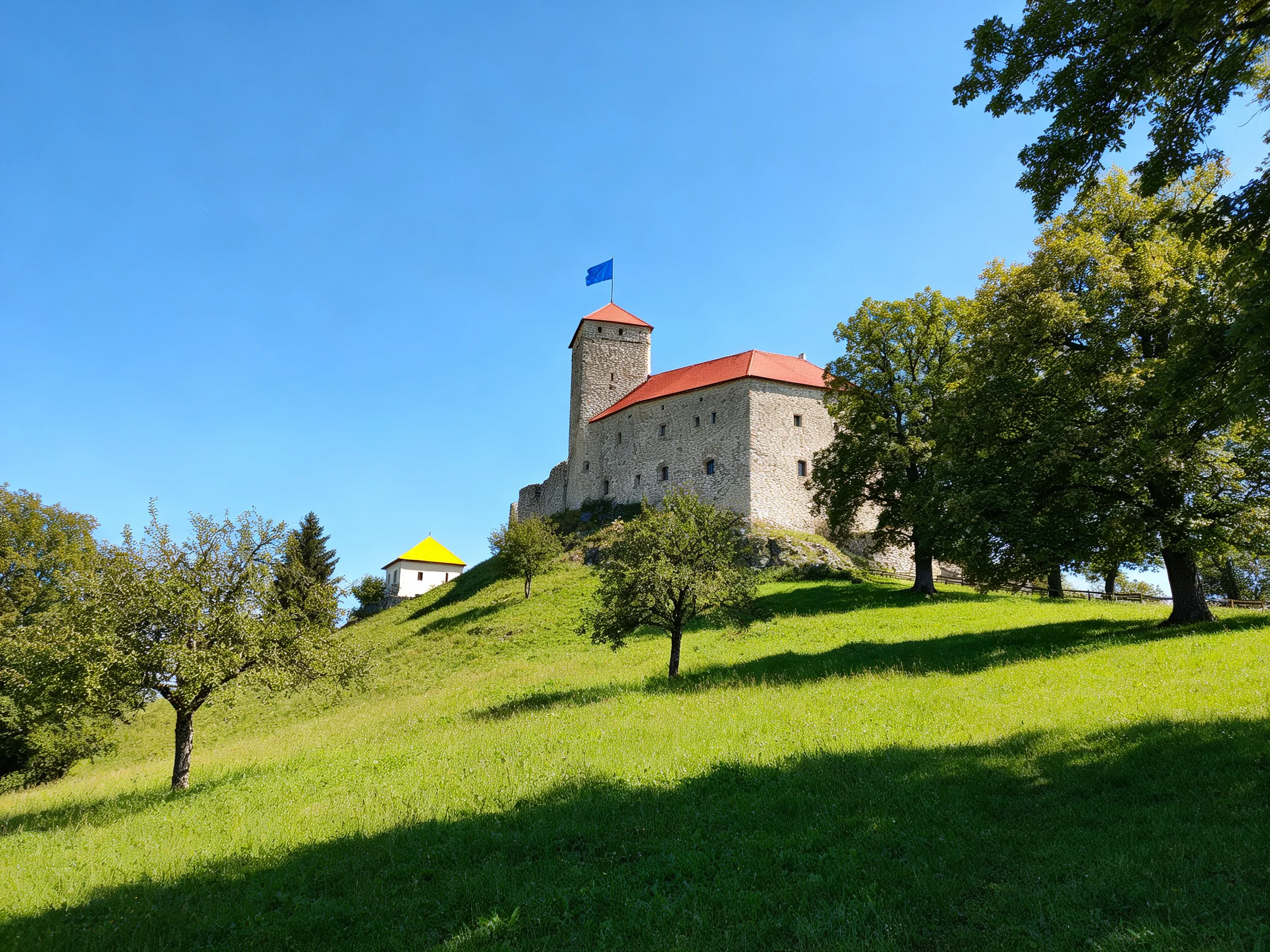 A historic stone castle with red roofs perched on a verdant hillside
