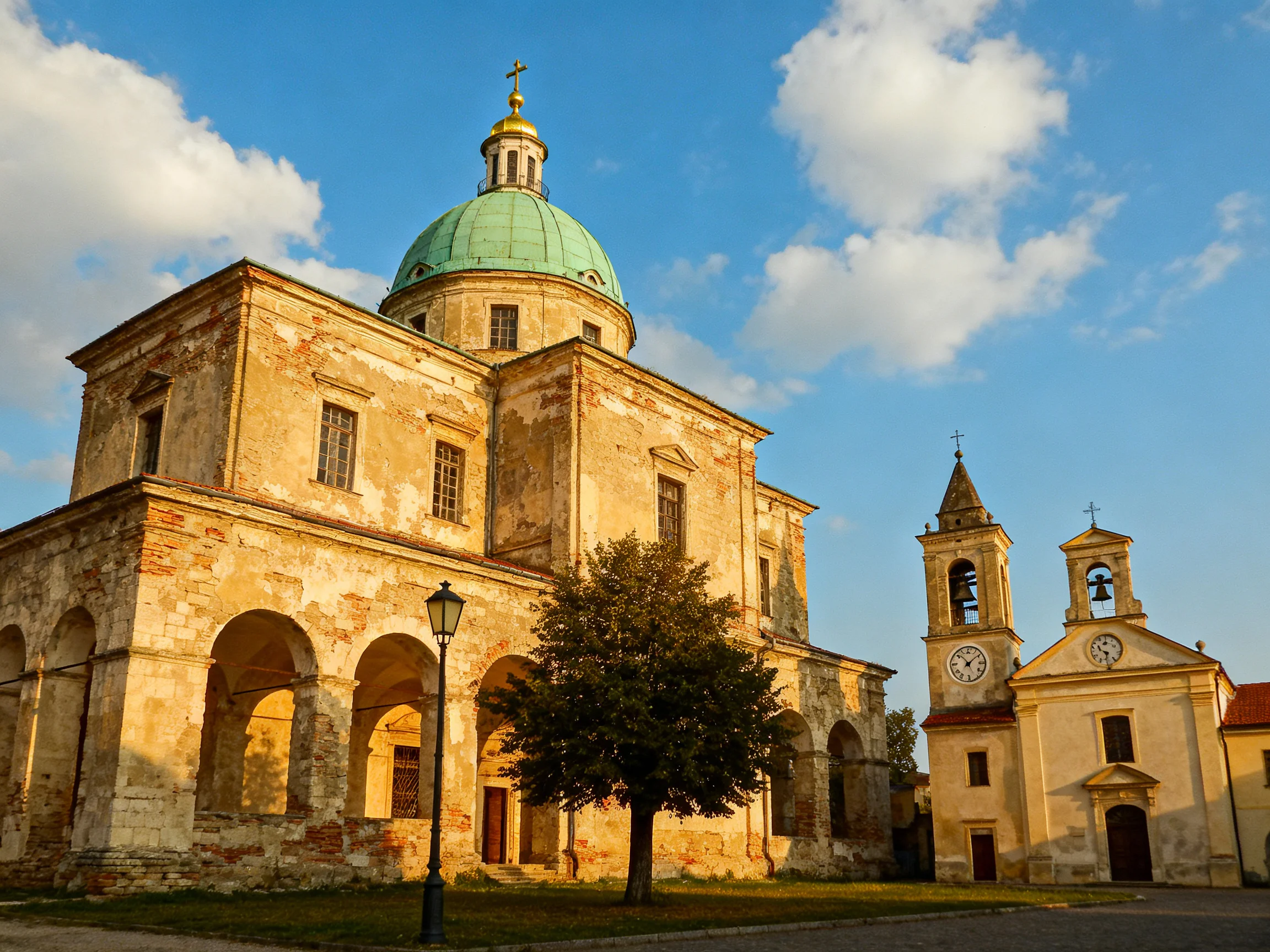 A historic stone church with a green dome beside clock towers