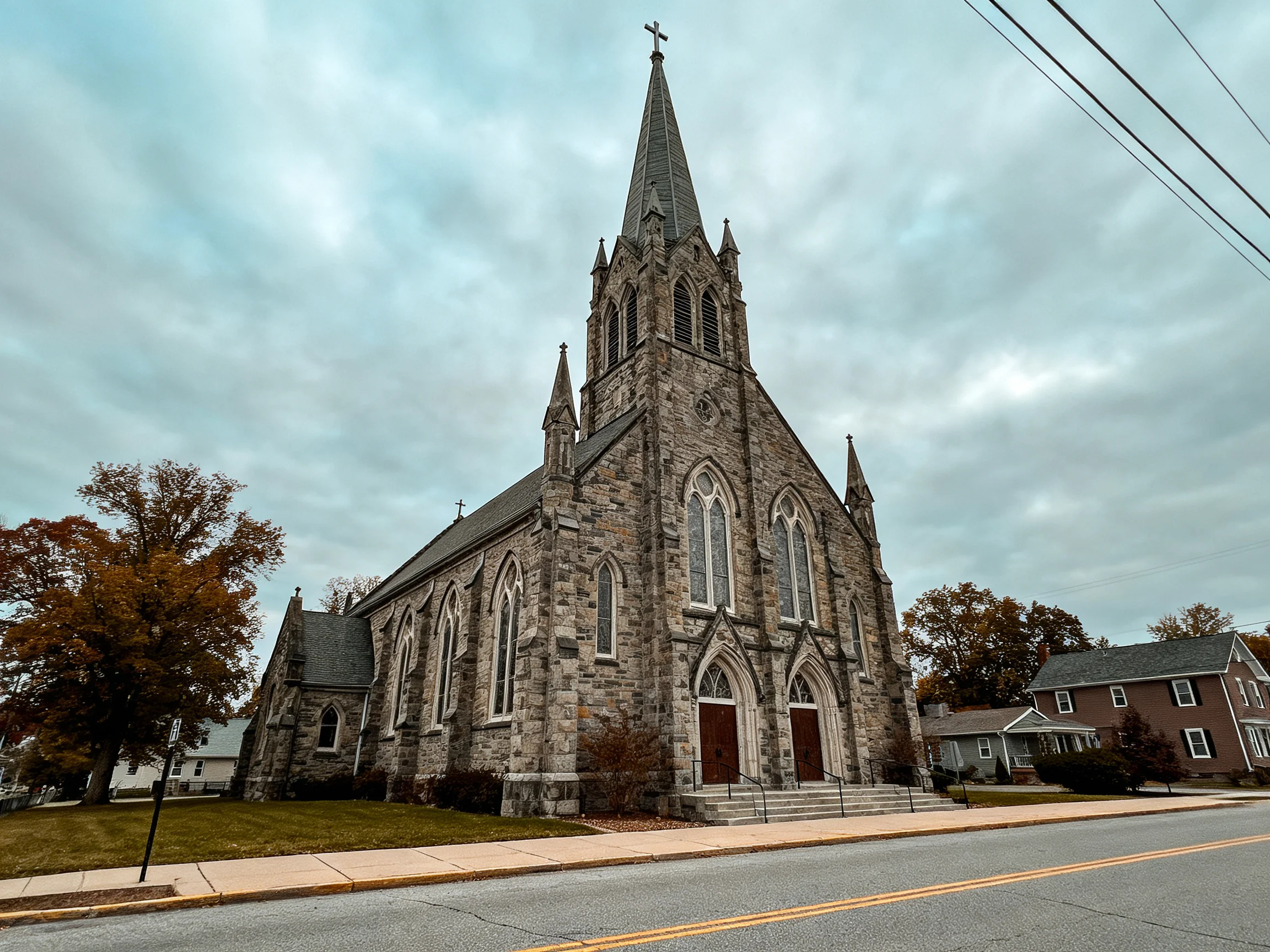 A historic stone church with a tall spire under an overcast sky
