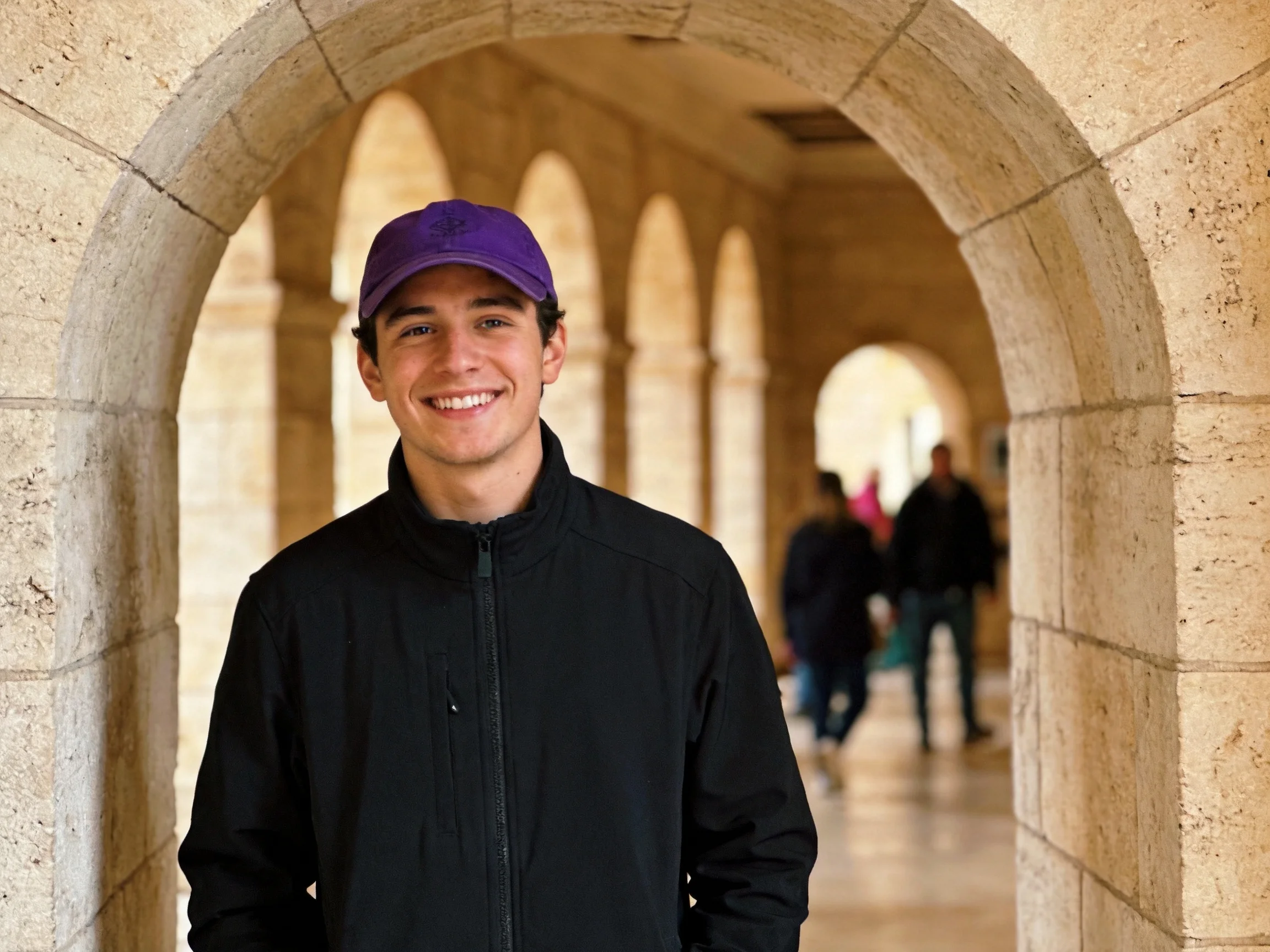 A man in a purple cap stands near stone archways with pedestrians