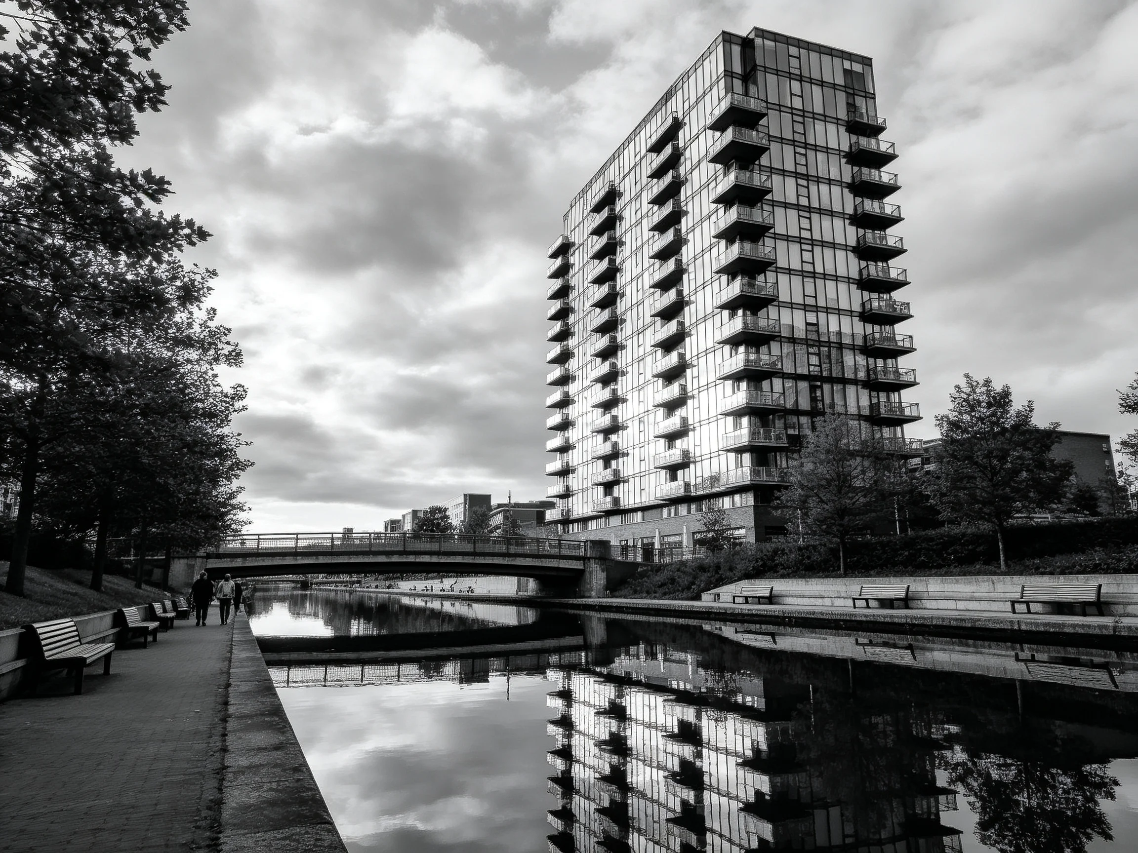 A modern glass high-rise reflects in urban canal scene