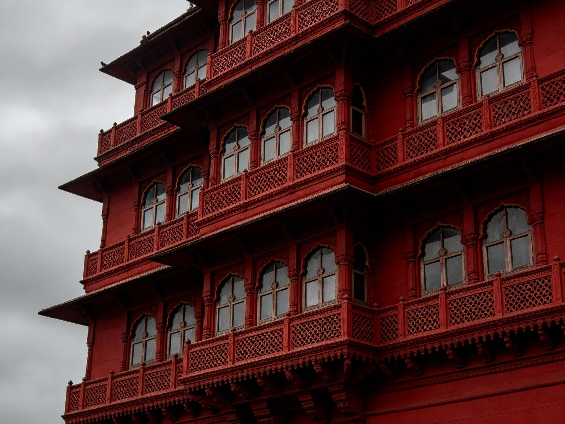 A multi-level red building with ornate balconies and arched windows