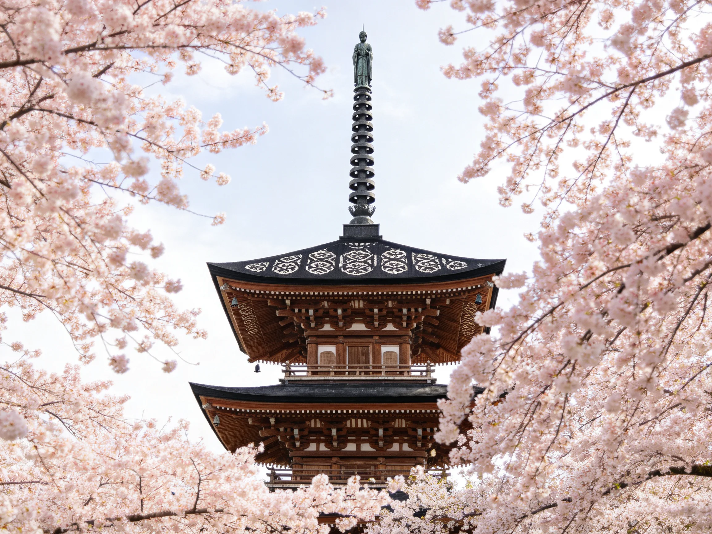 A multi - tiered pagoda tower framed by pink cherry blossom branches