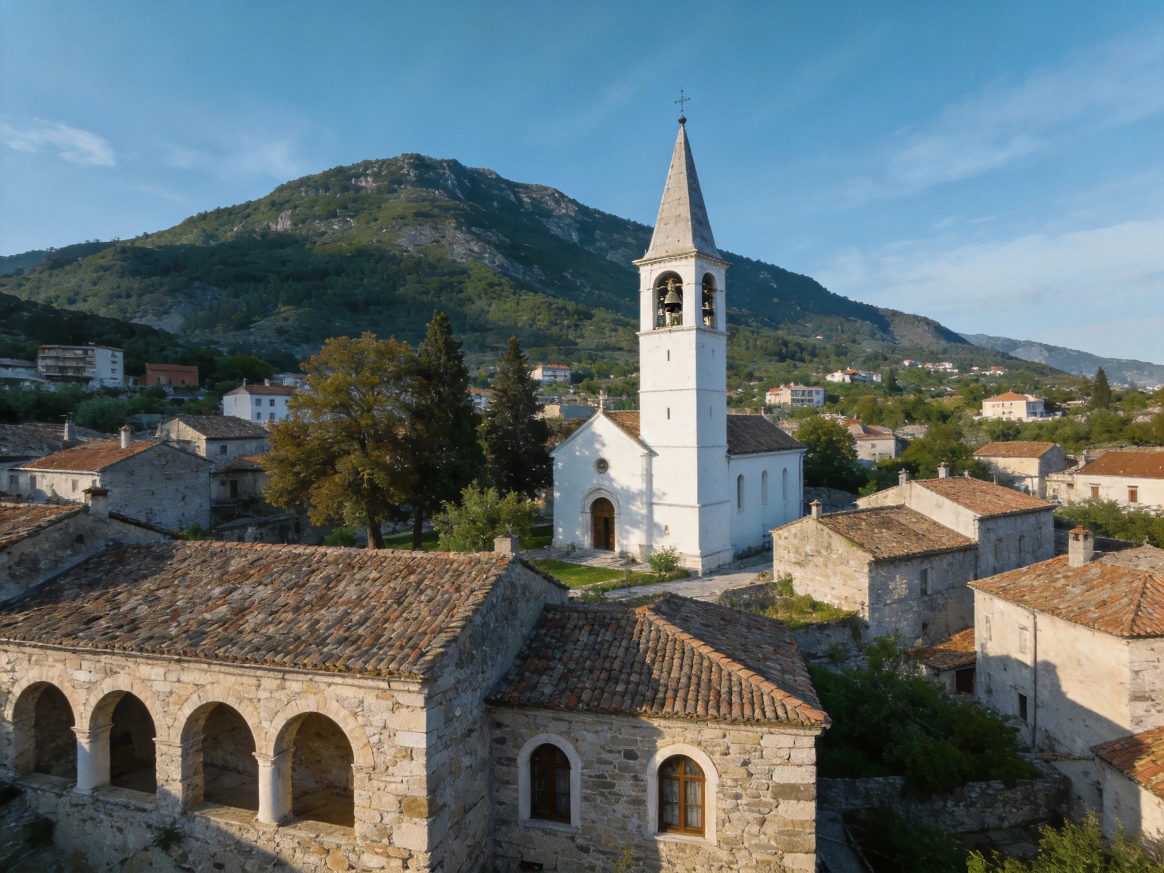 A quaint village with a tall white church near green mountains