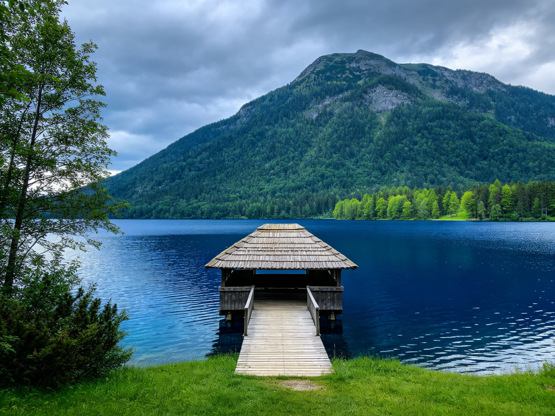 A rustic dock extends into serene blue lake near forested mountain