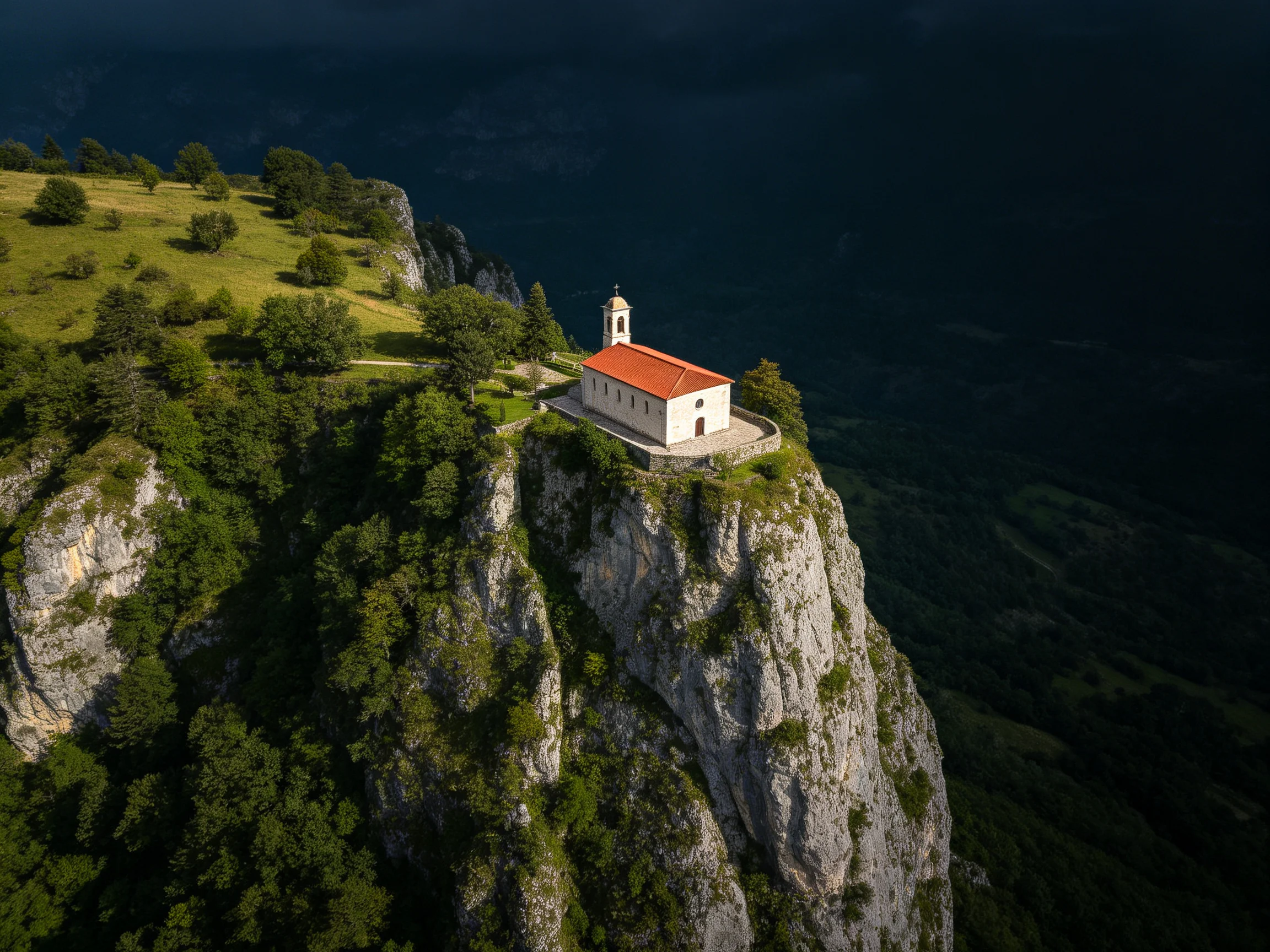 A small church with a red roof atop a steep cliffside