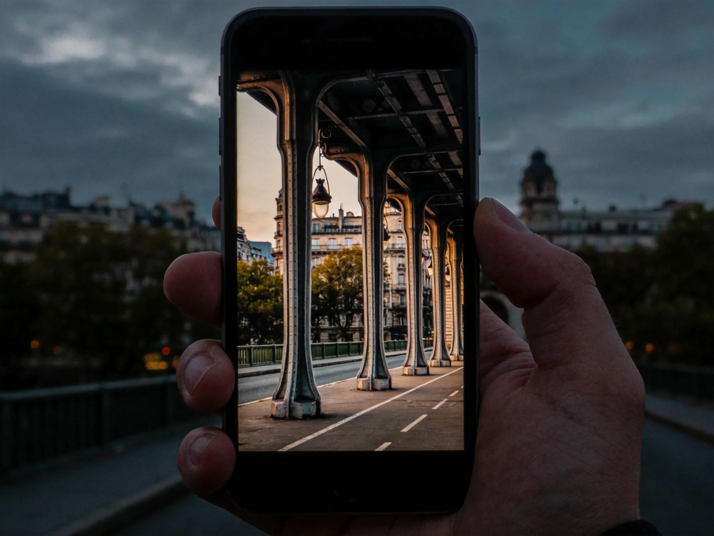 A smartphone frames ornate columns of a historic urban bridge