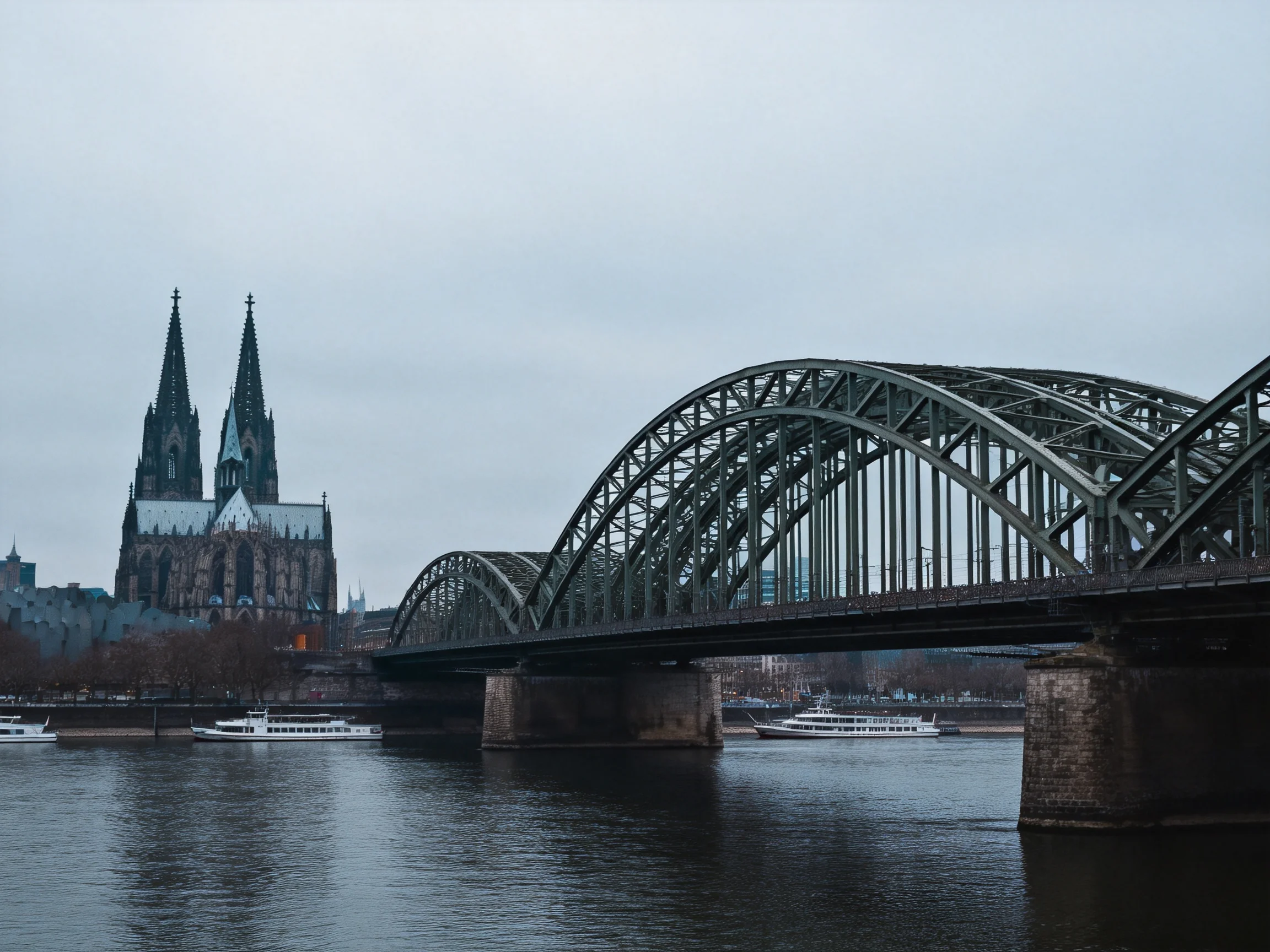 A steel arch bridge spans a calm river near a Gothic cathedral