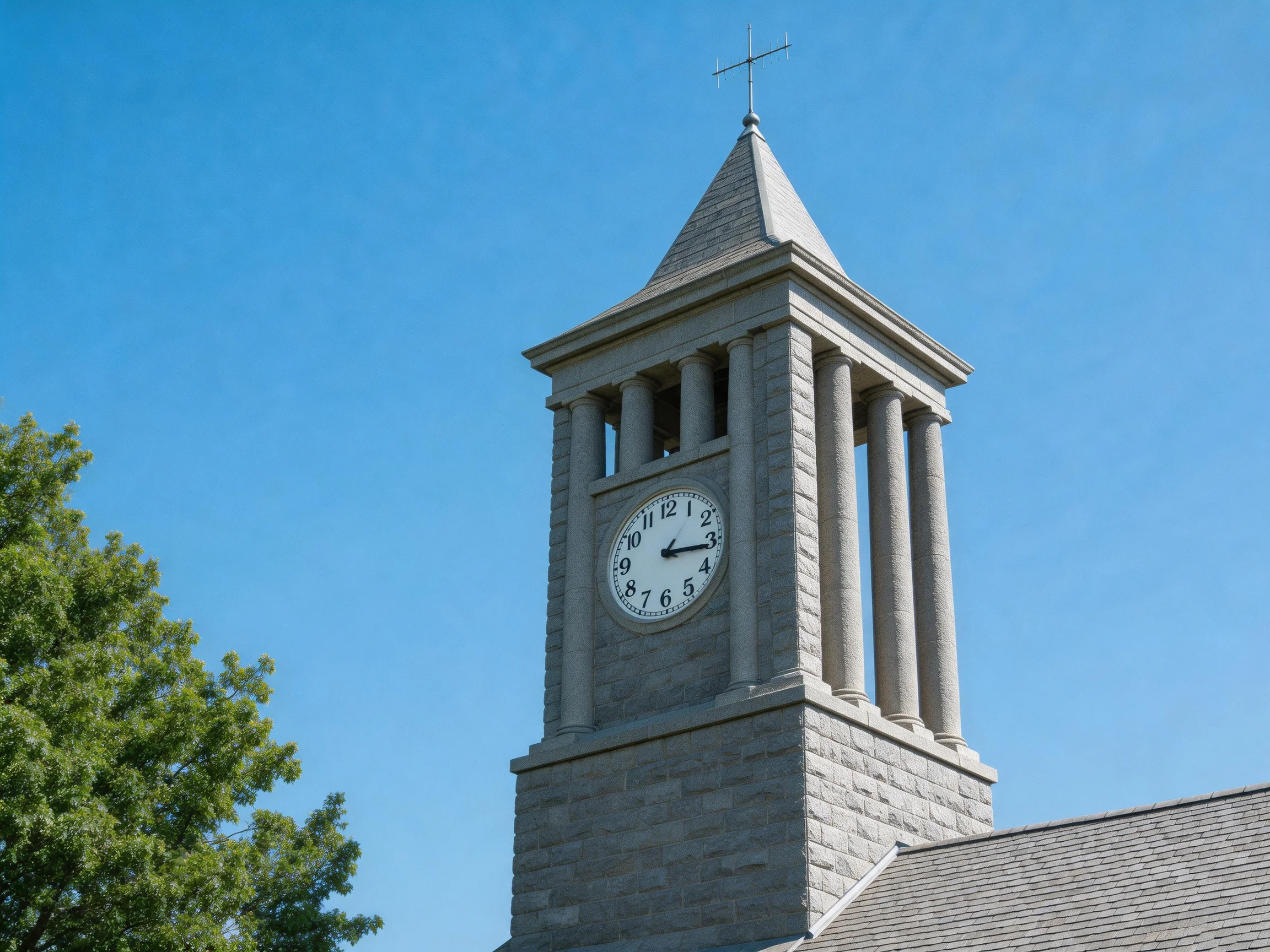 A stone clock tower with columns under a clear blue sky