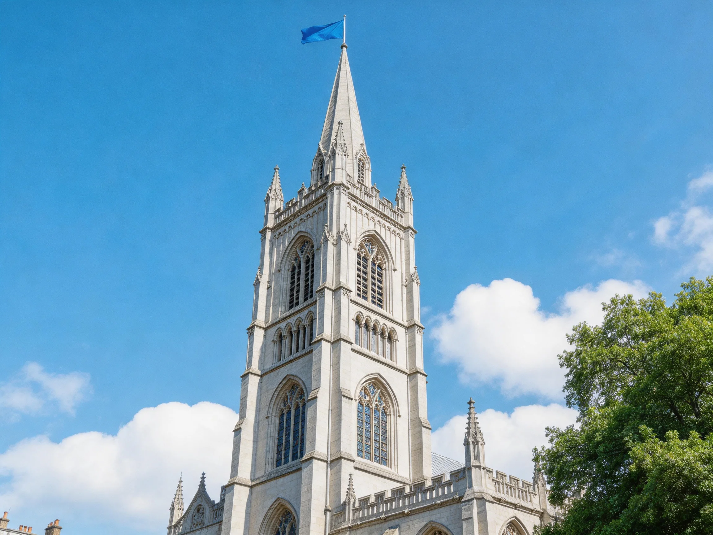 A tall stone church tower with a blue flag against bright sky