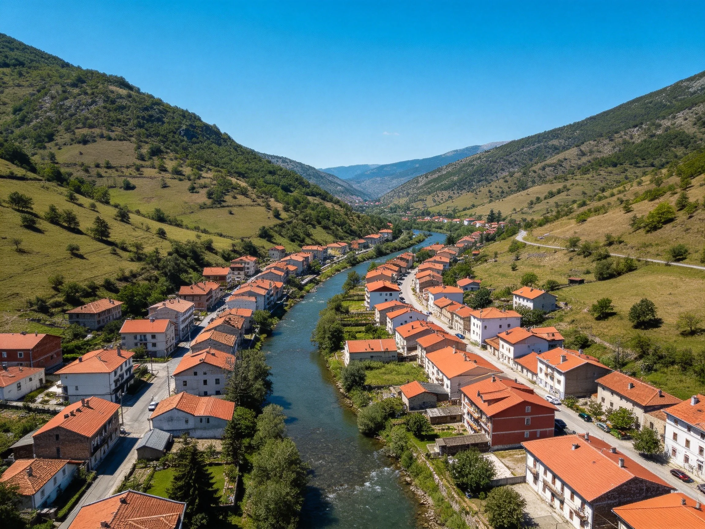 A village with red-tiled roofs along a winding river between green mountains