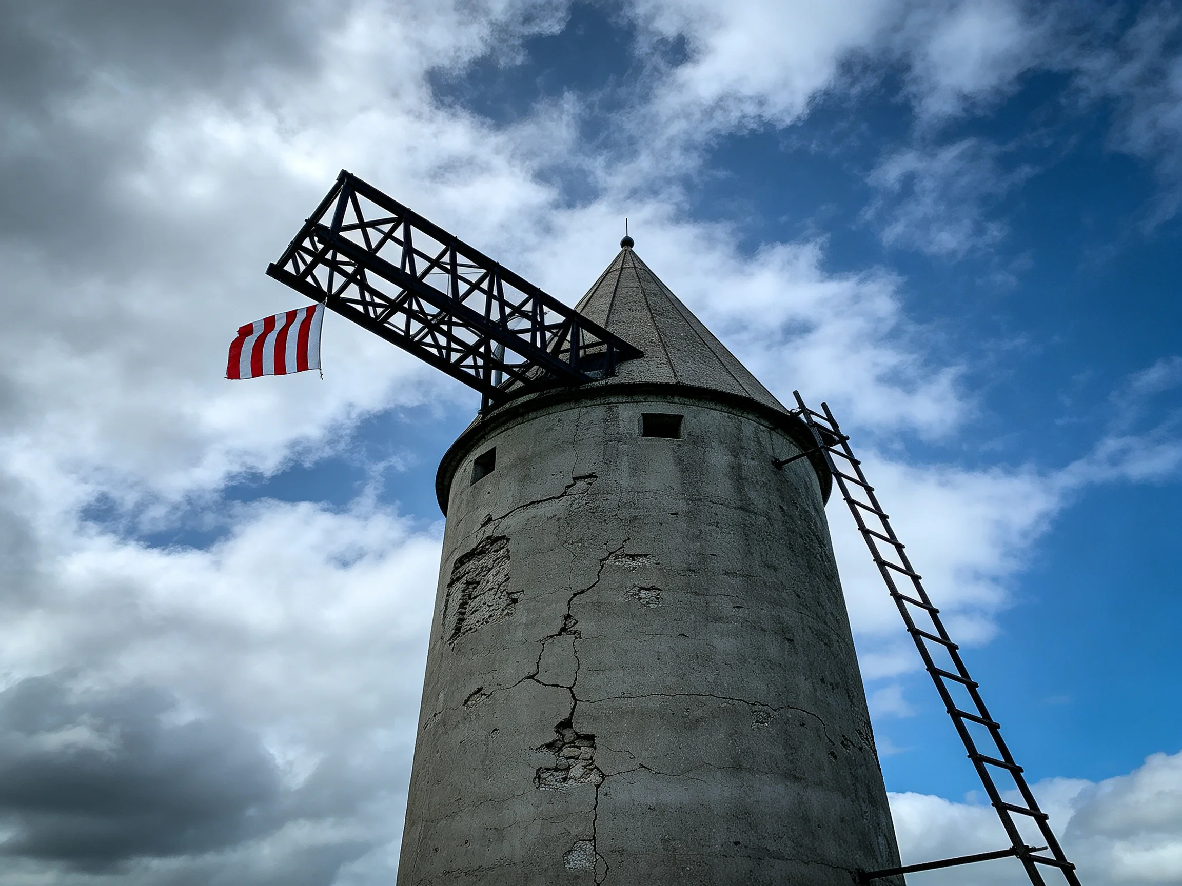 A weathered concrete tower with a striped flag and metal framework