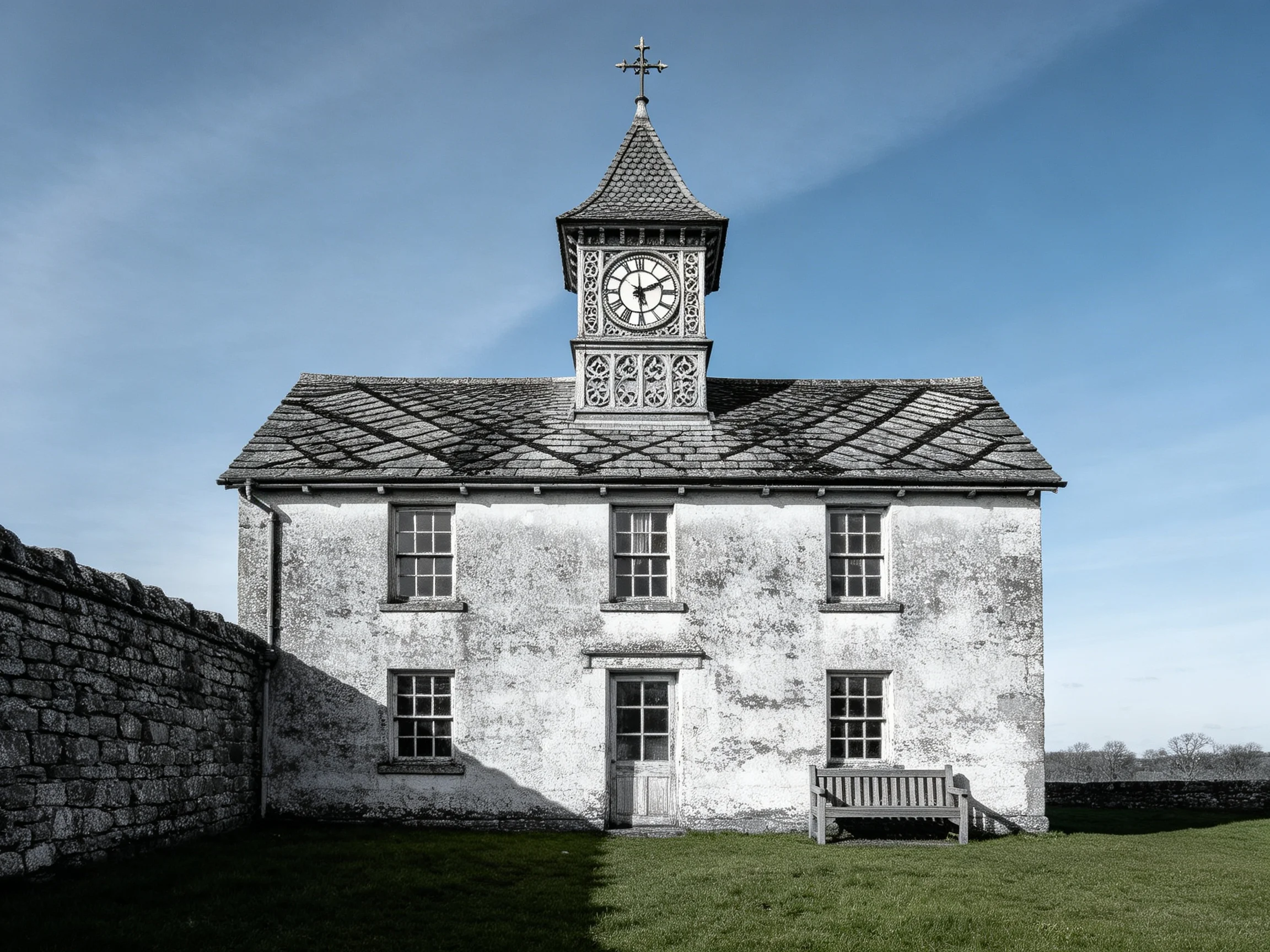 A weathered stone building with clock tower and wooden bench