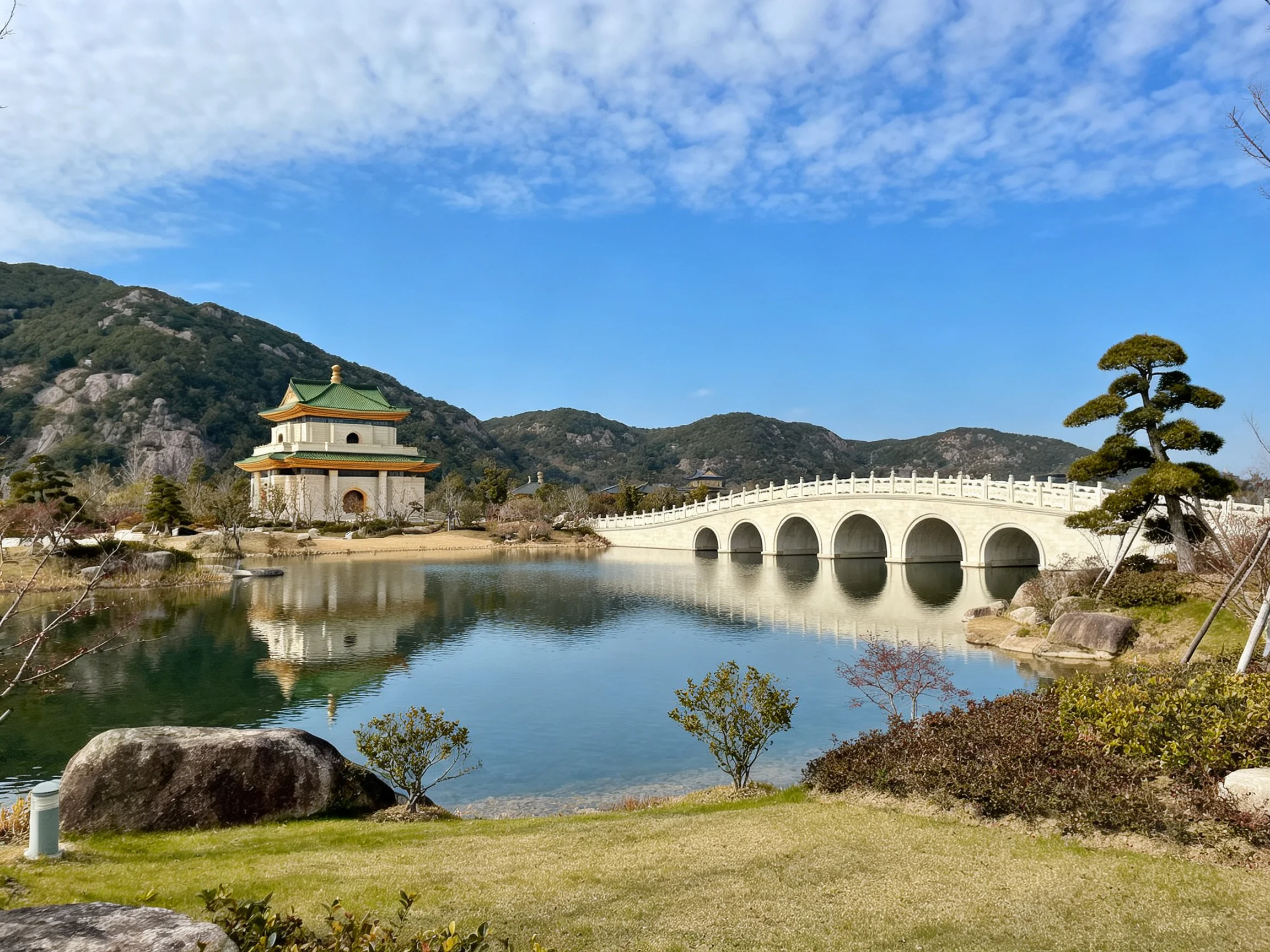 A white multi-arch bridge spans a calm lake near a green-roofed temple