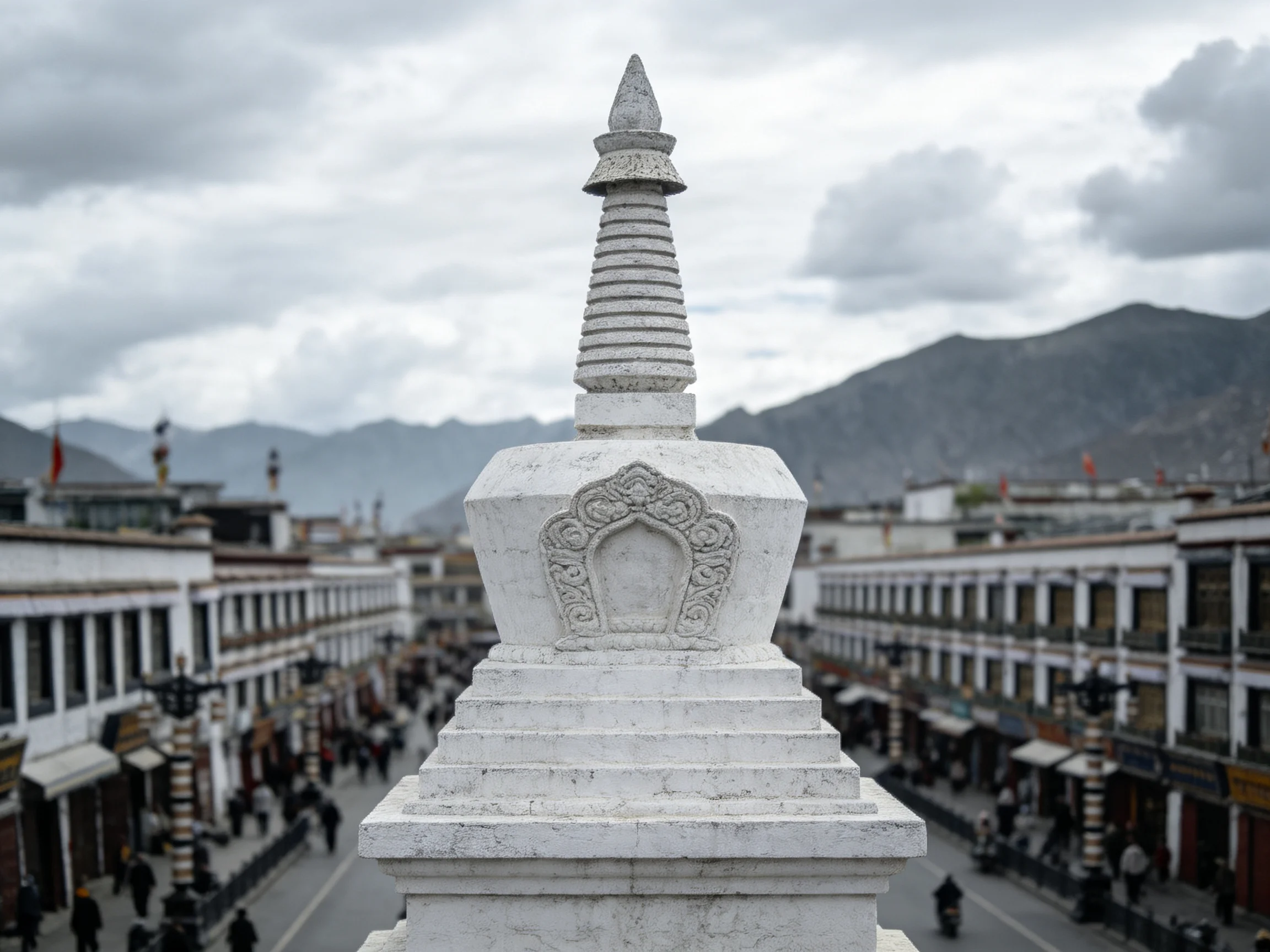 A white stone stupa overlooks a bustling Tibetan-style town with distant mountains
