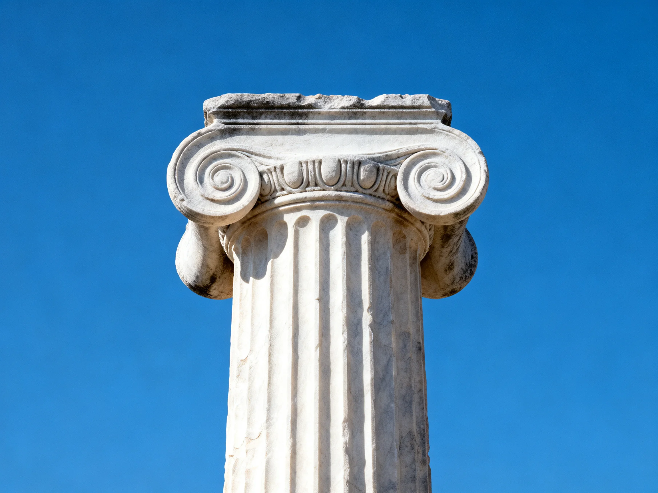 An ancient white marble column with decorative scroll capitals