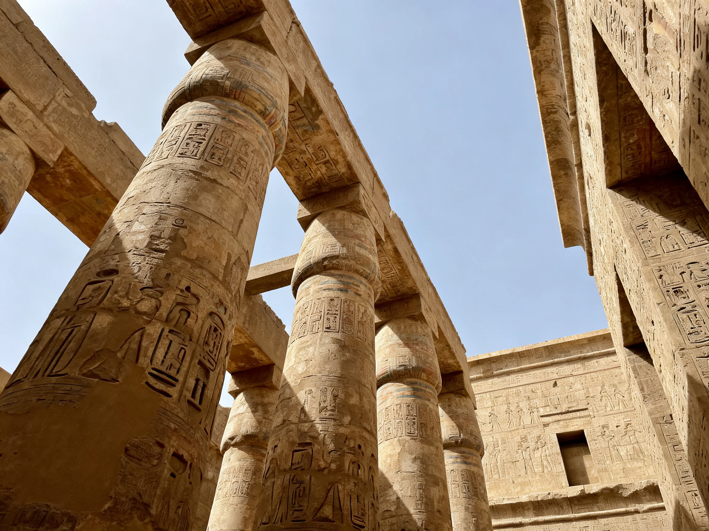 Ancient Egyptian temple’s massive sandstone columns display intricate hieroglyphic carvings