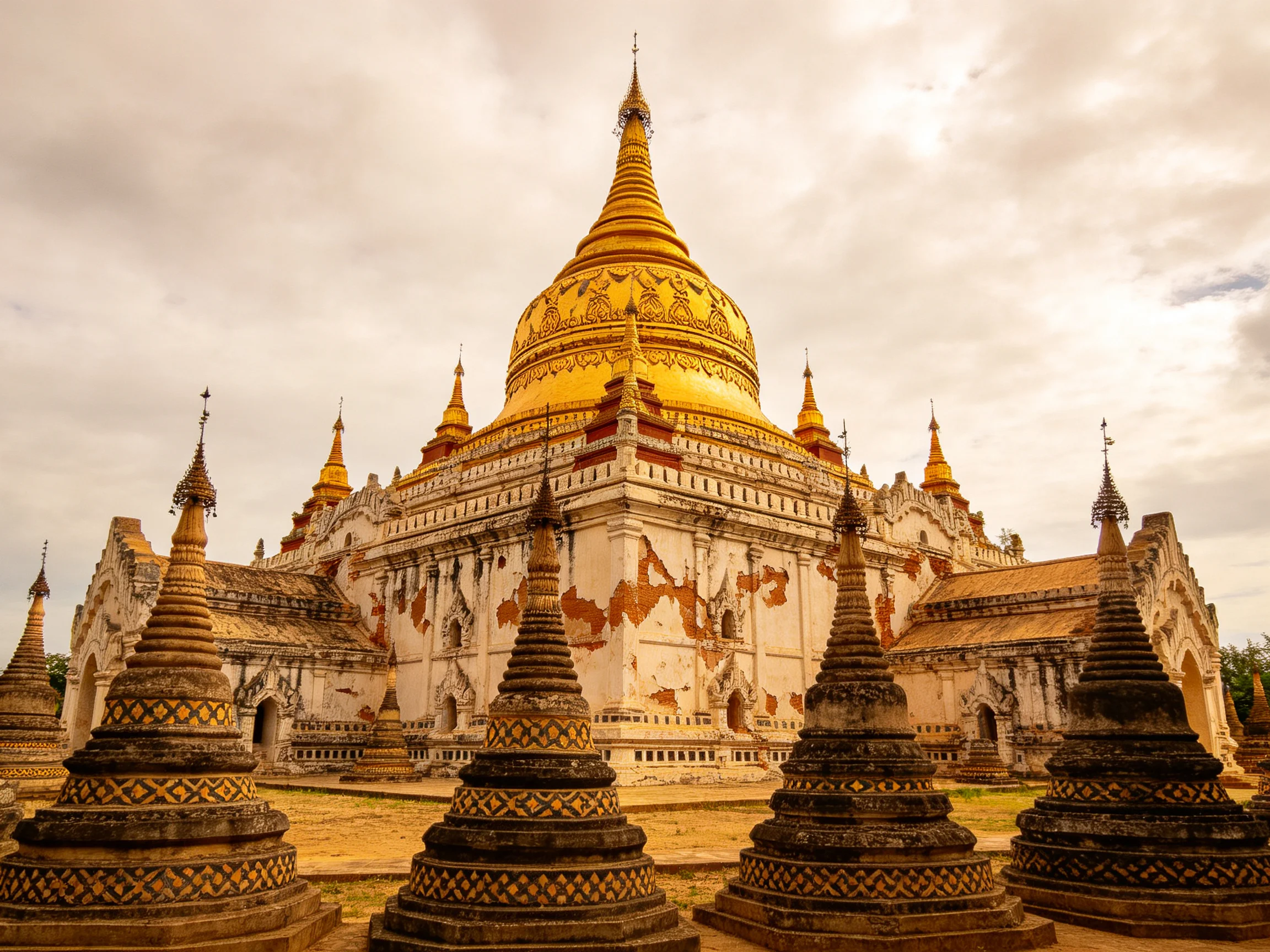 Ancient Golden Temple Complex with Weathered Walls and Smaller Stupas