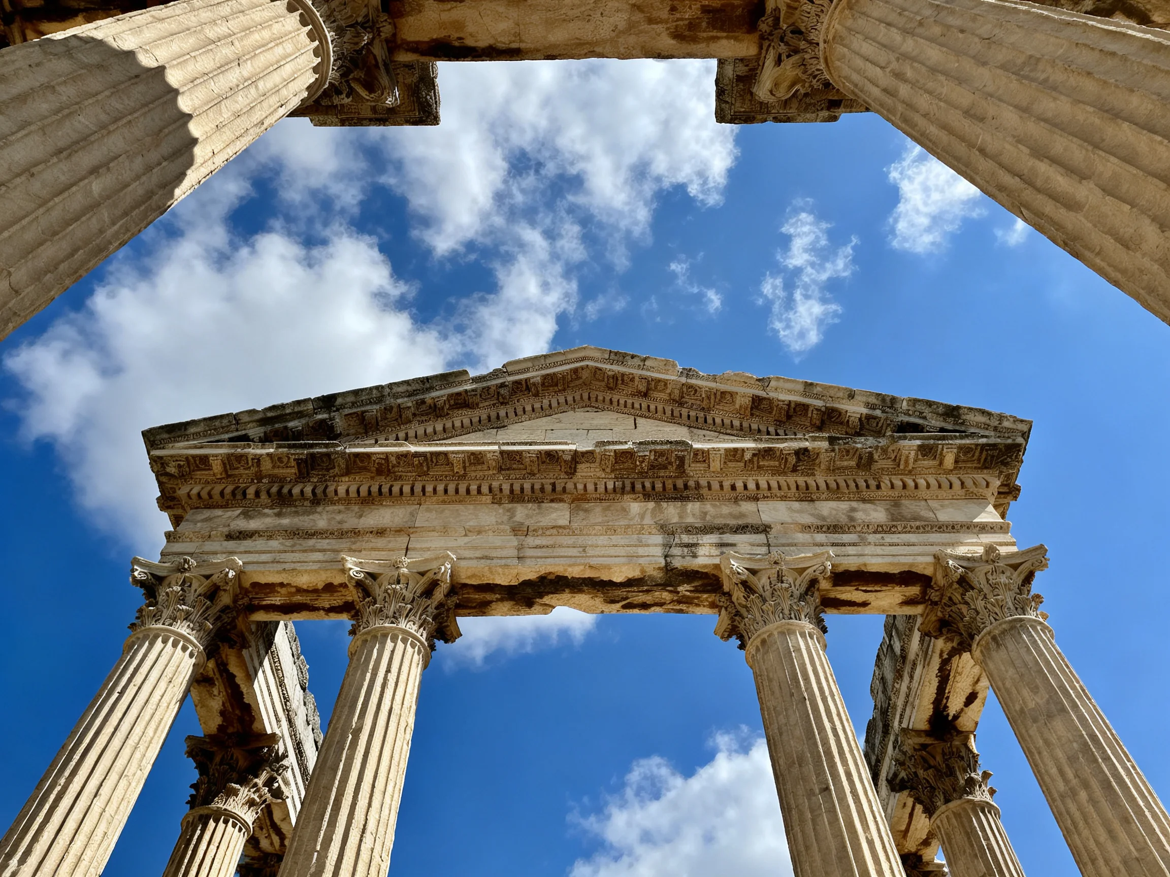 Ancient Roman Temple Ruins with Tall Fluted Stone Columns Against Bright Blue Sky