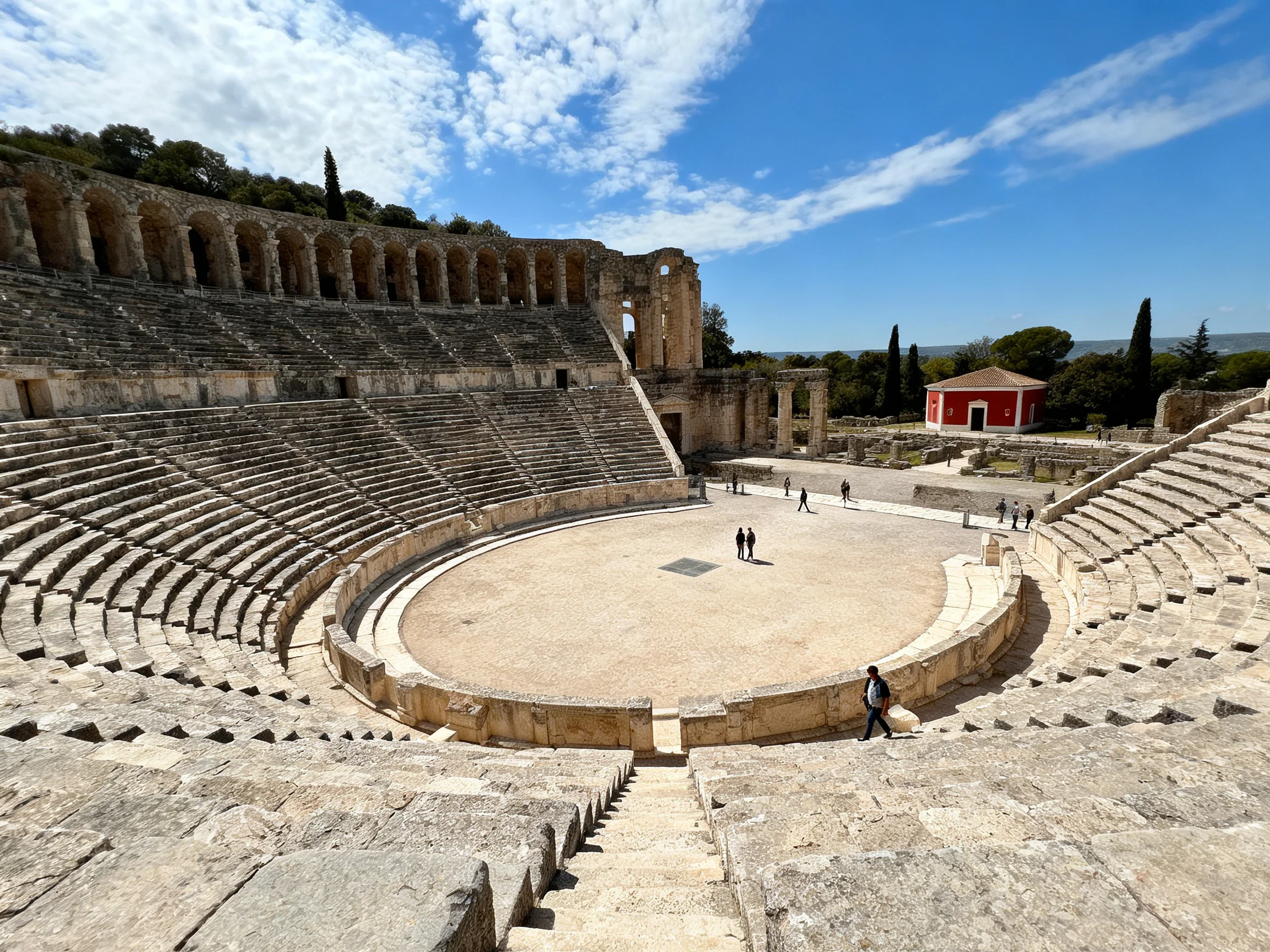 Ancient Stone Amphitheater with Red Building and Clear Blue Sky