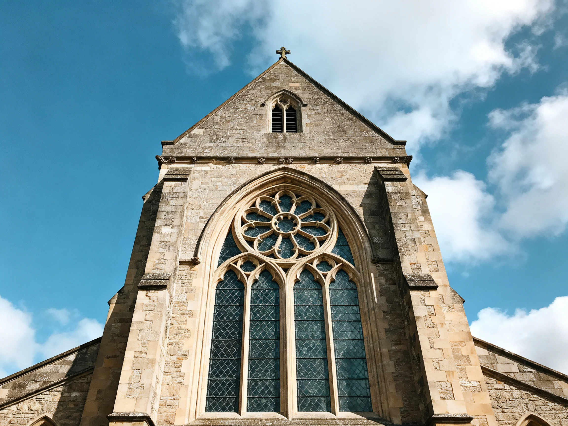 Ancient stone church tower with ornate rose window and cross