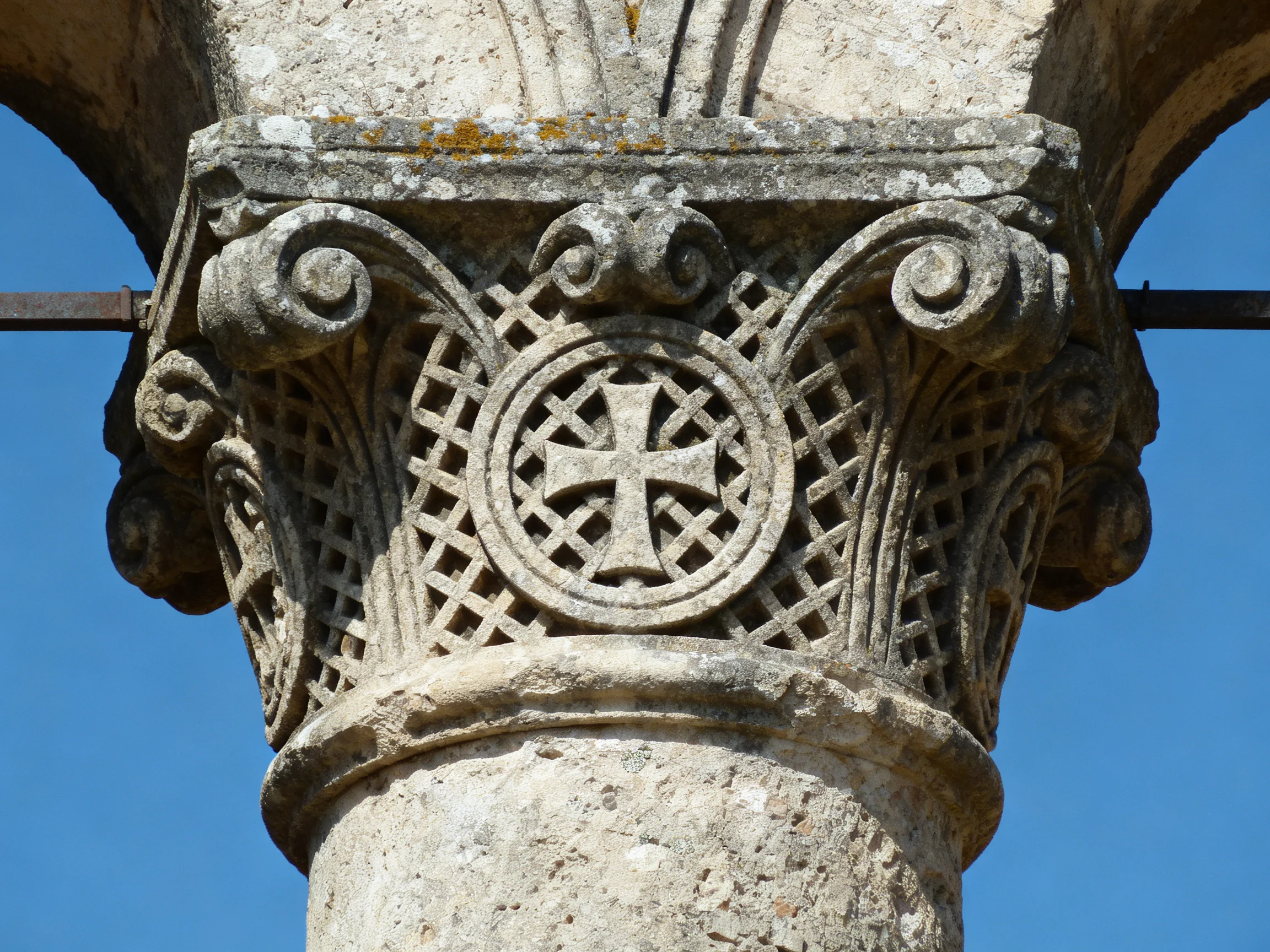 Ancient stone column capital with intricate carvings and central cross