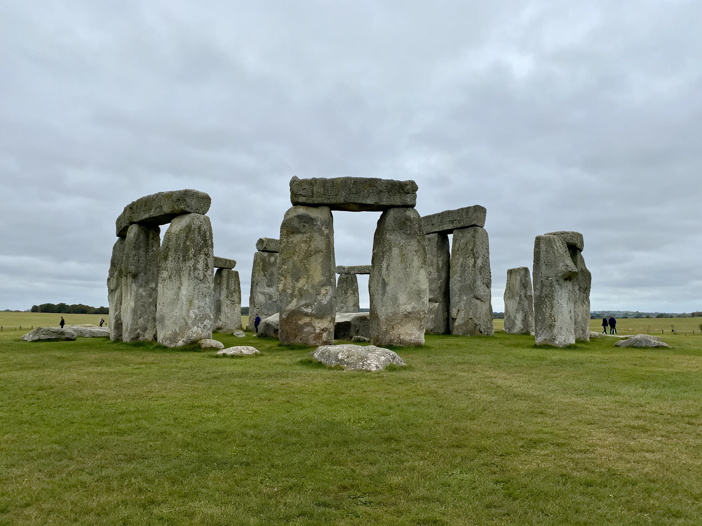 Ancient stone monument with large gray stones on green grass under overcast sky