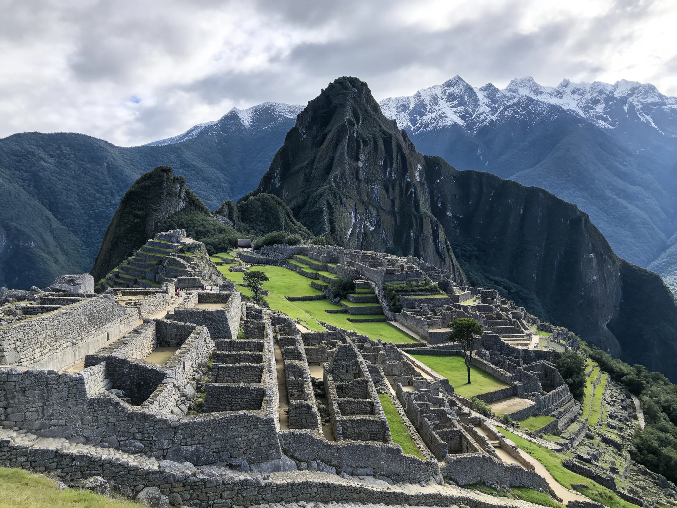 Ancient stone ruins with green terraces near snow - capped mountains
