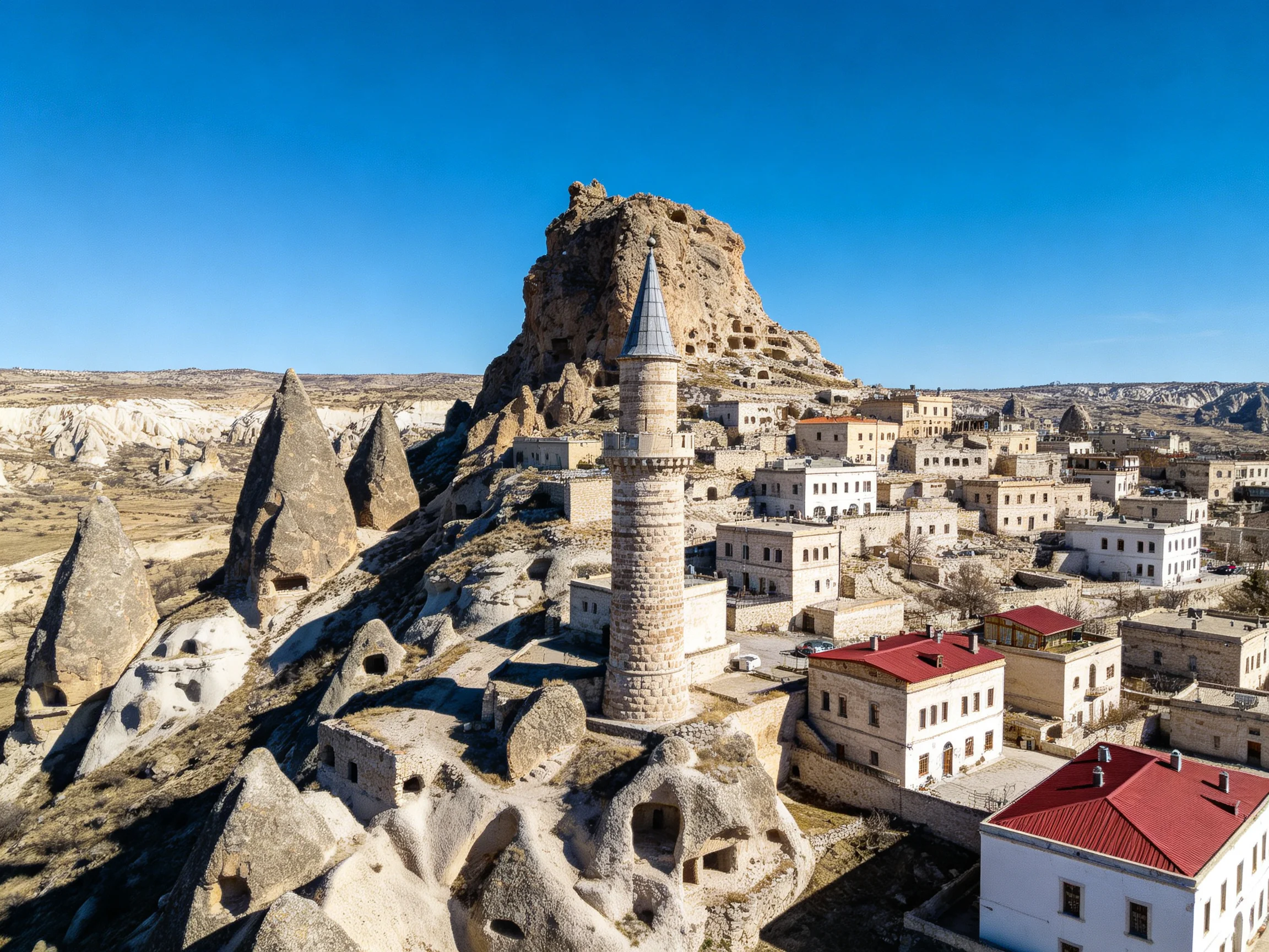 Ancient stone village with a tall minaret near rocky cliffs