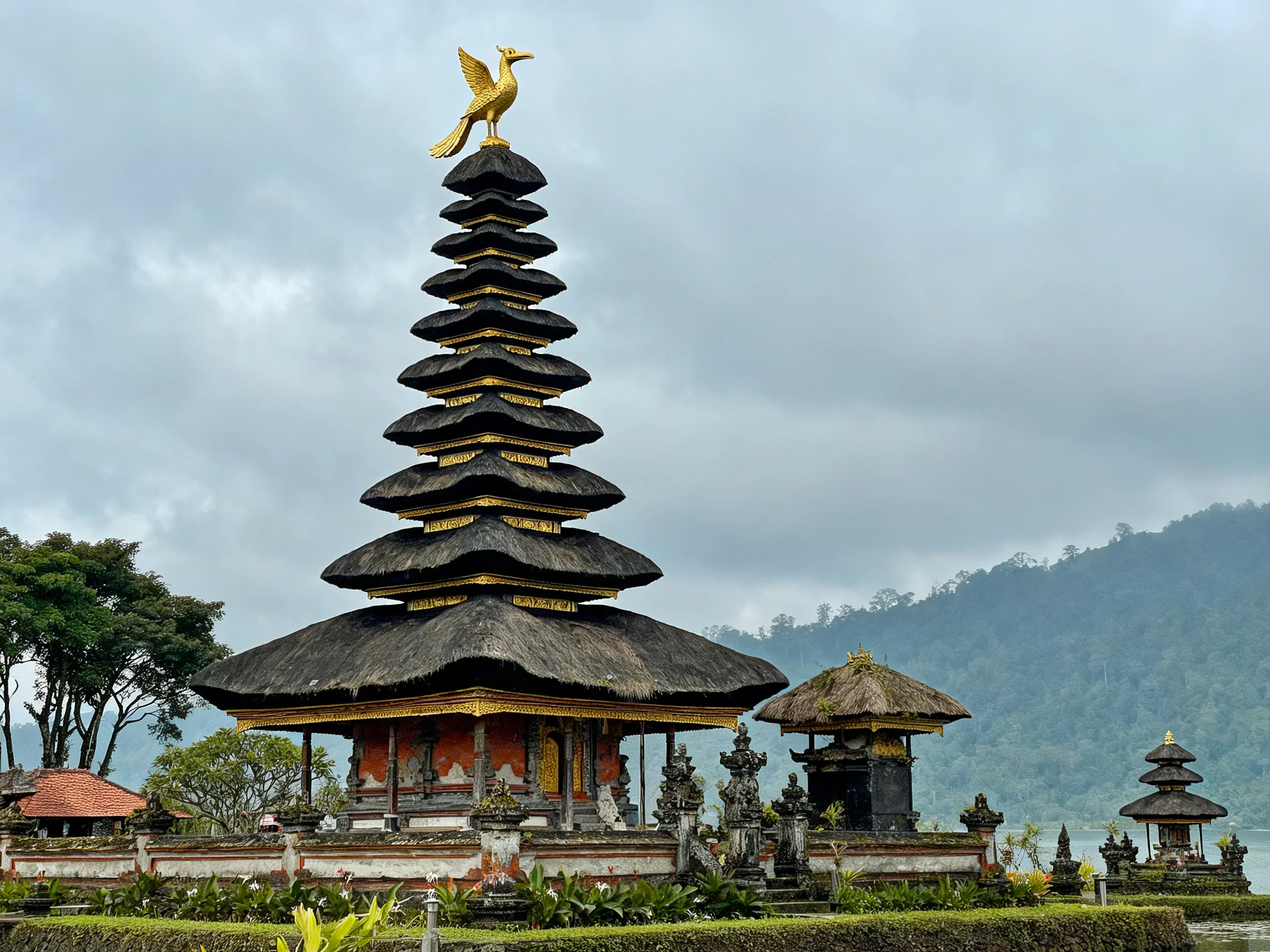 Balinese temple with golden bird statue, near misty mountains