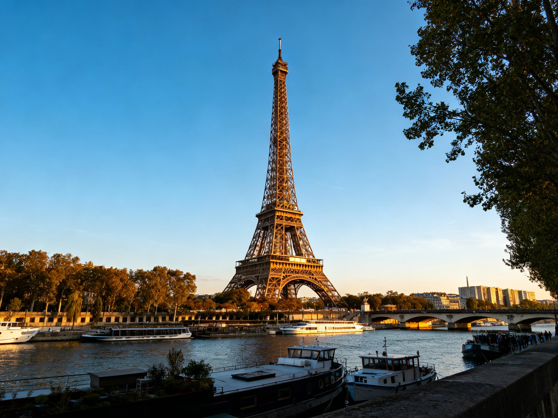 Eiffel Tower stands tall by the Seine River with boats and golden light
