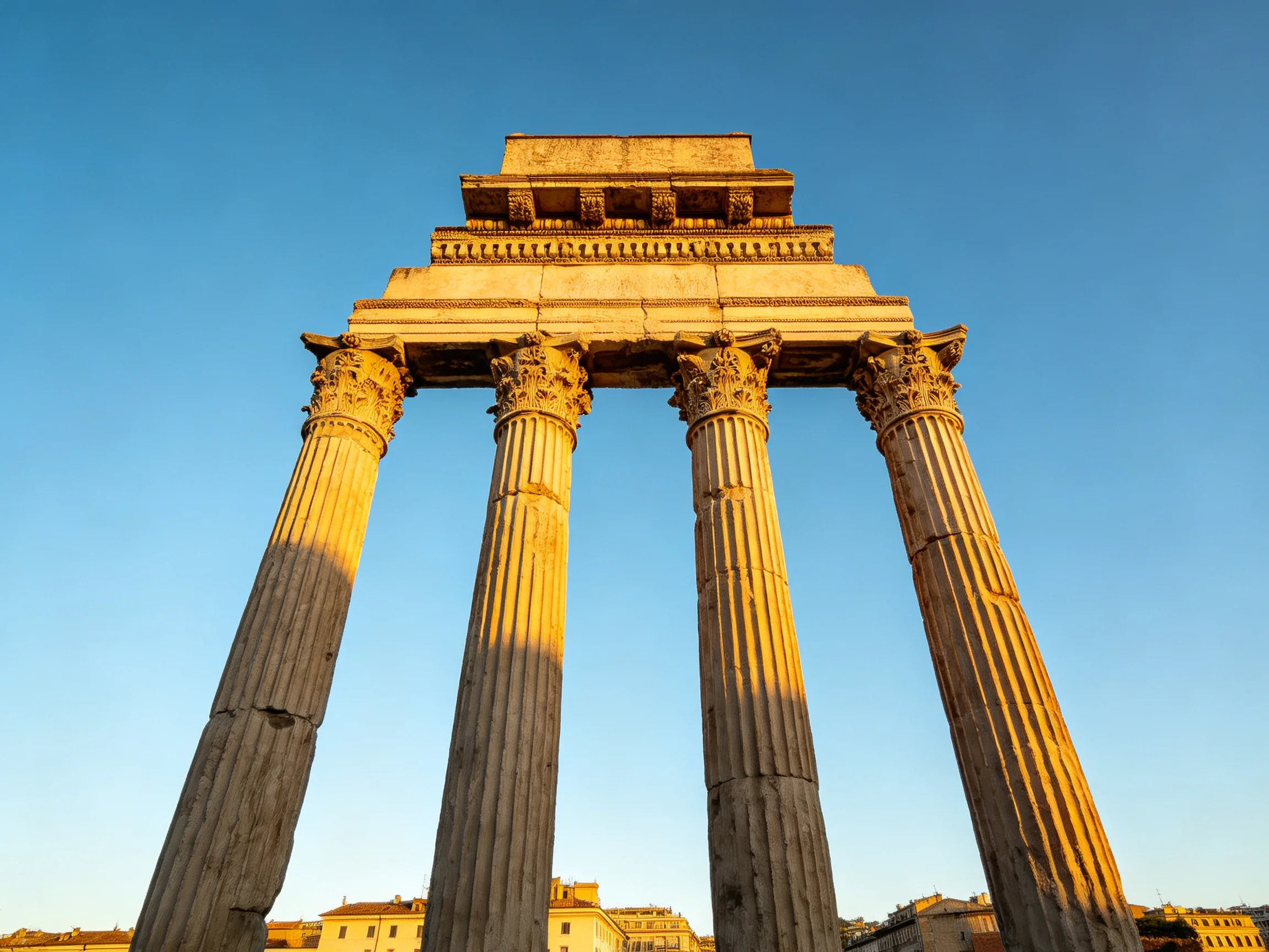 Four ancient stone columns support a historic temple remnant under clear blue sky