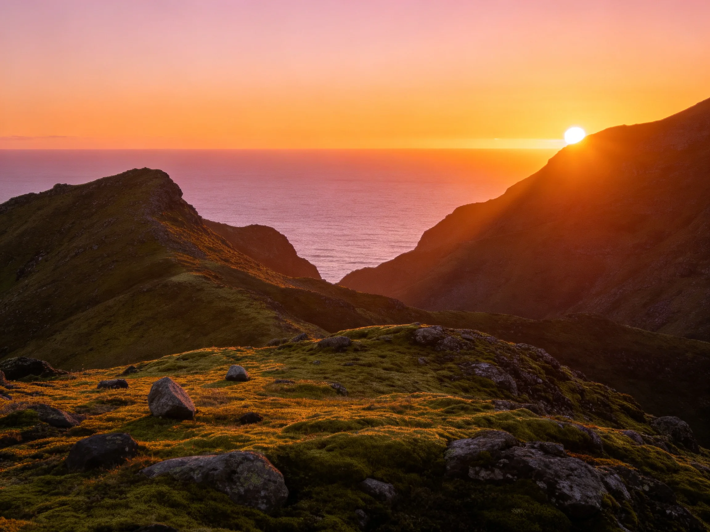 Golden sunset over mossy mountain ridges by tranquil ocean