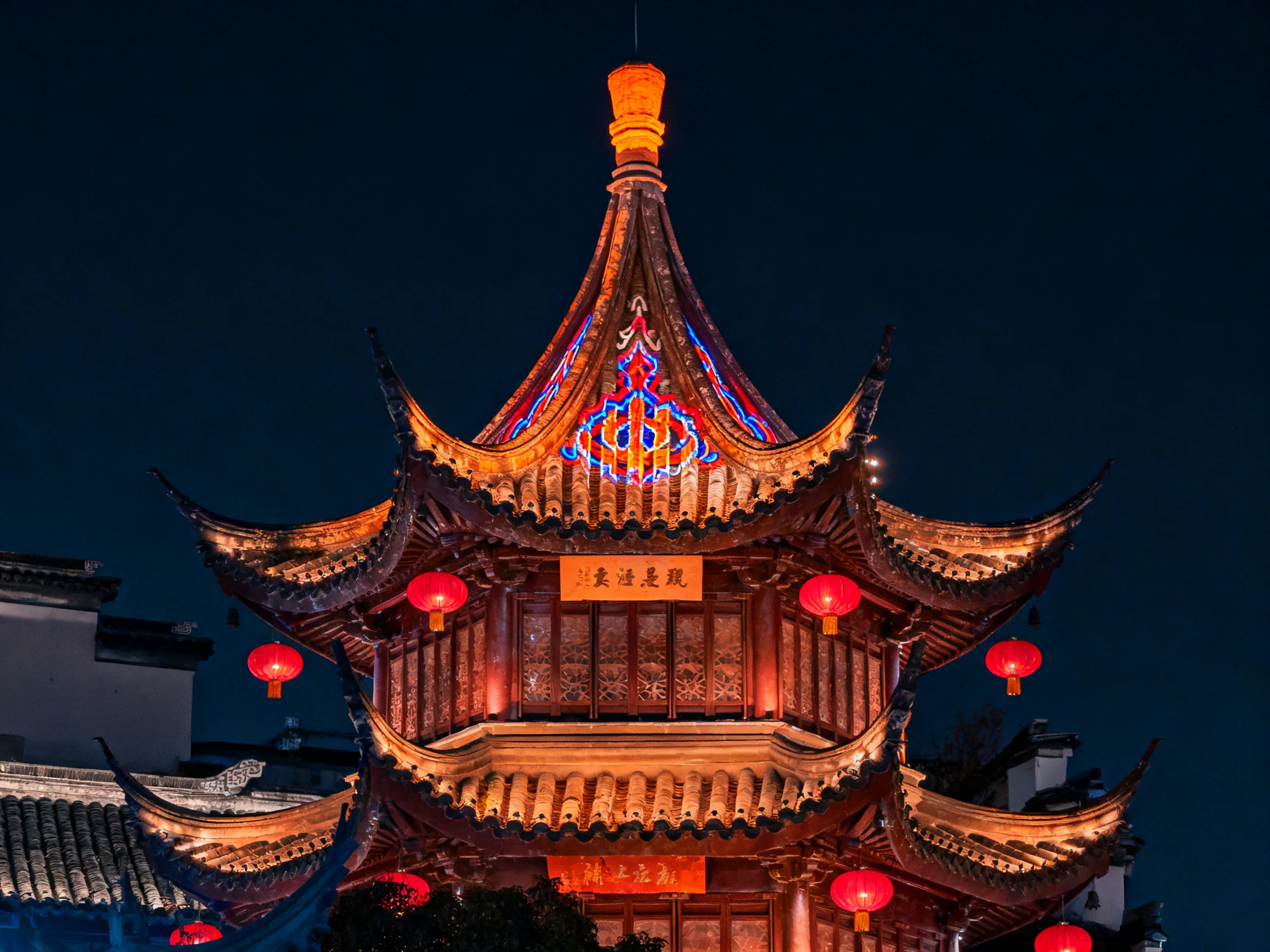 Illuminated multi-tiered pagoda with red lanterns and colorful stained glass