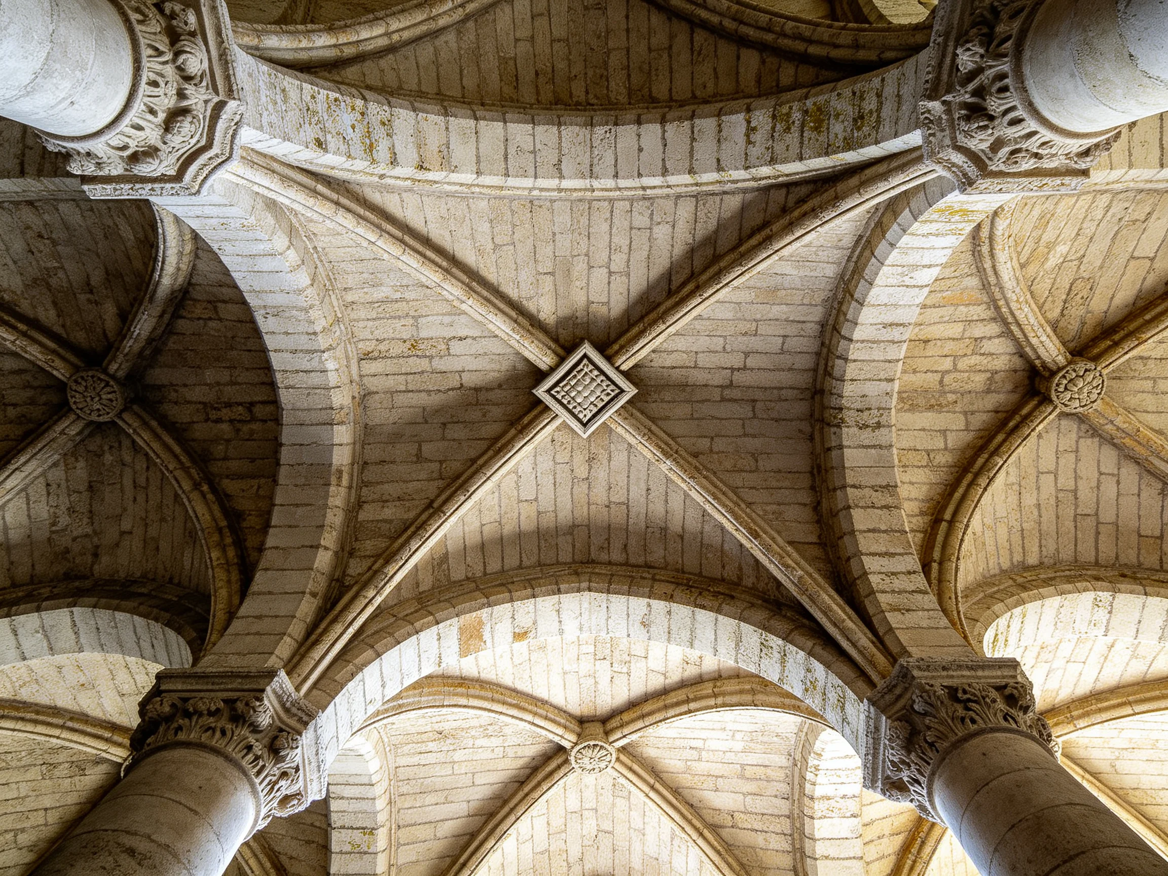 Intricate Stone Vaulted Ceiling with Ornate Columns and Arched Brickwork