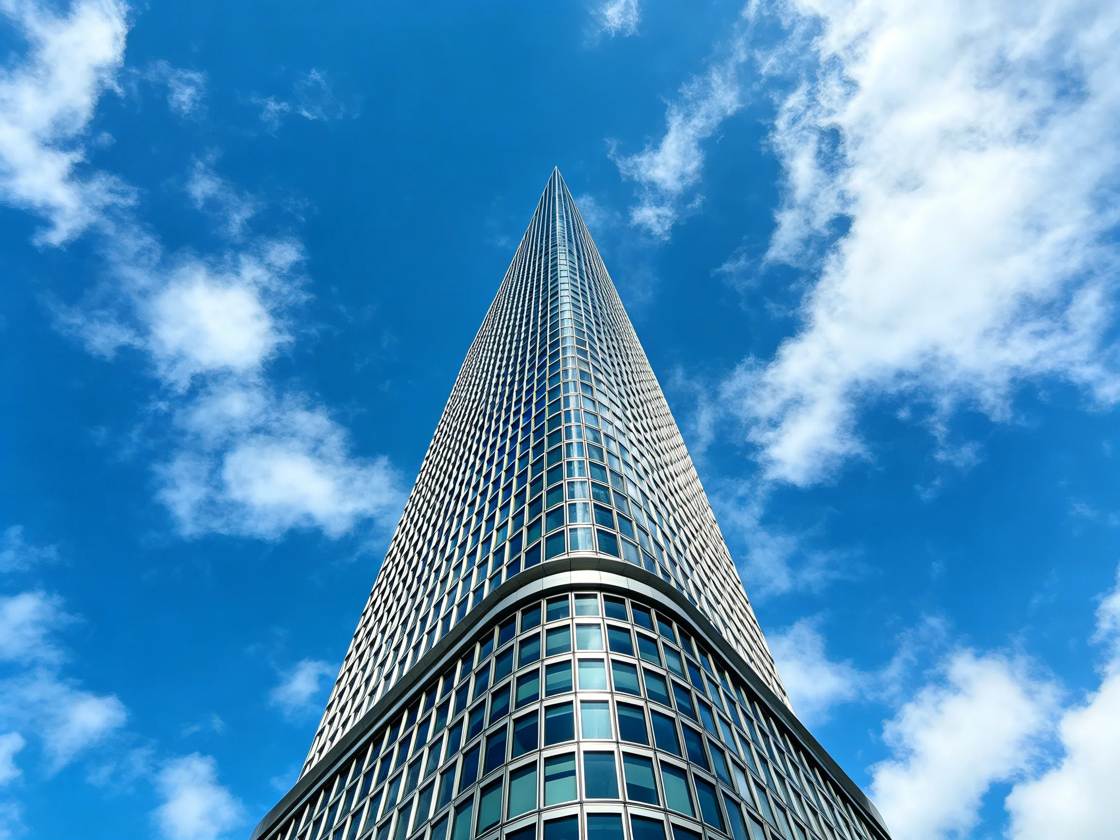 Modern skyscraper with glass facade under bright blue sky