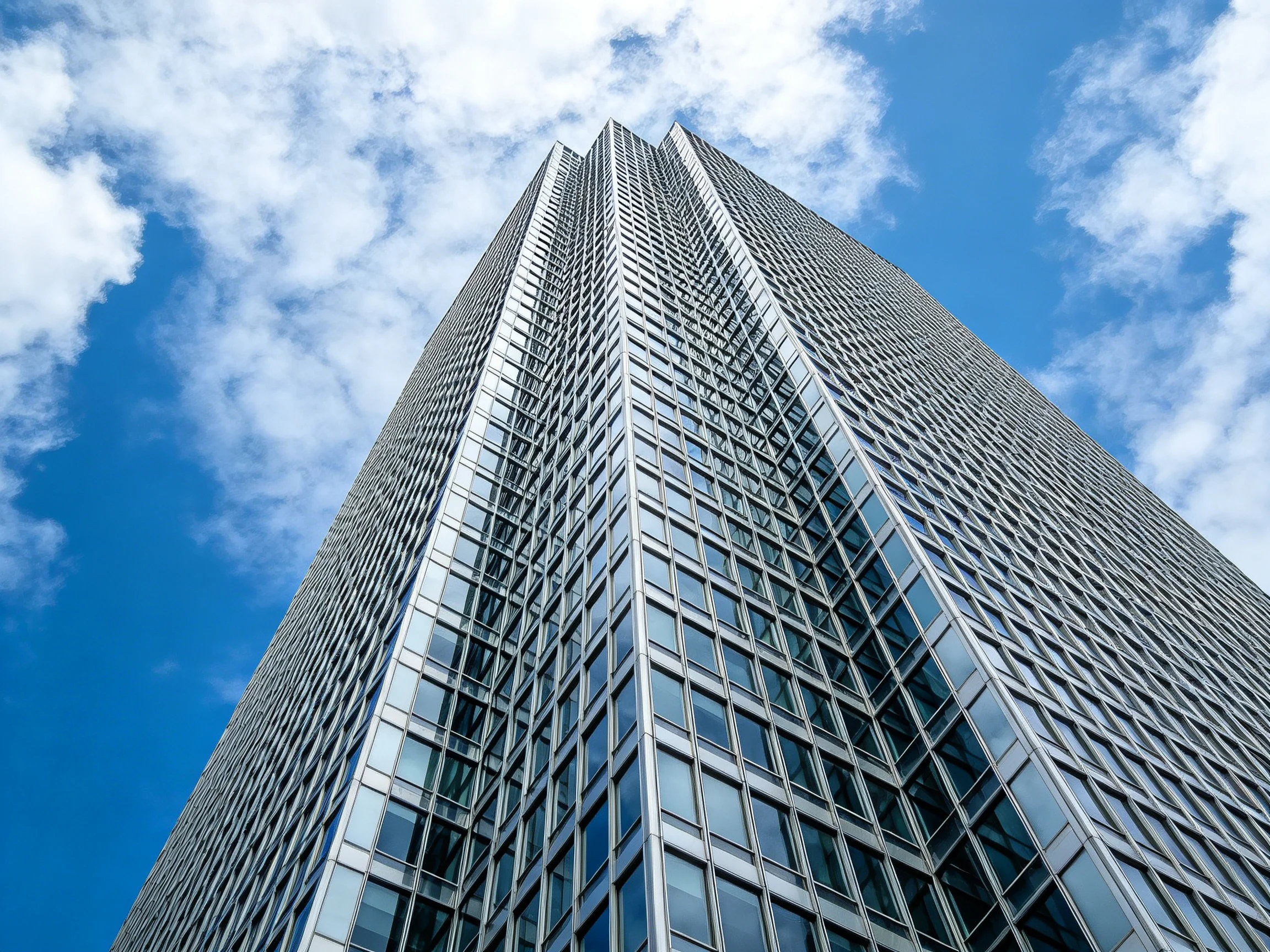 Modern skyscraper with reflective glass facade under bright blue sky
