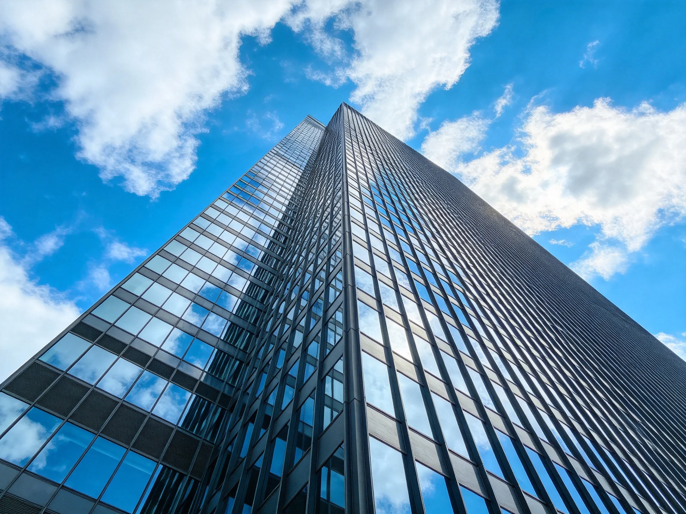 Modern skyscraper with reflective glass facade under bright blue sky