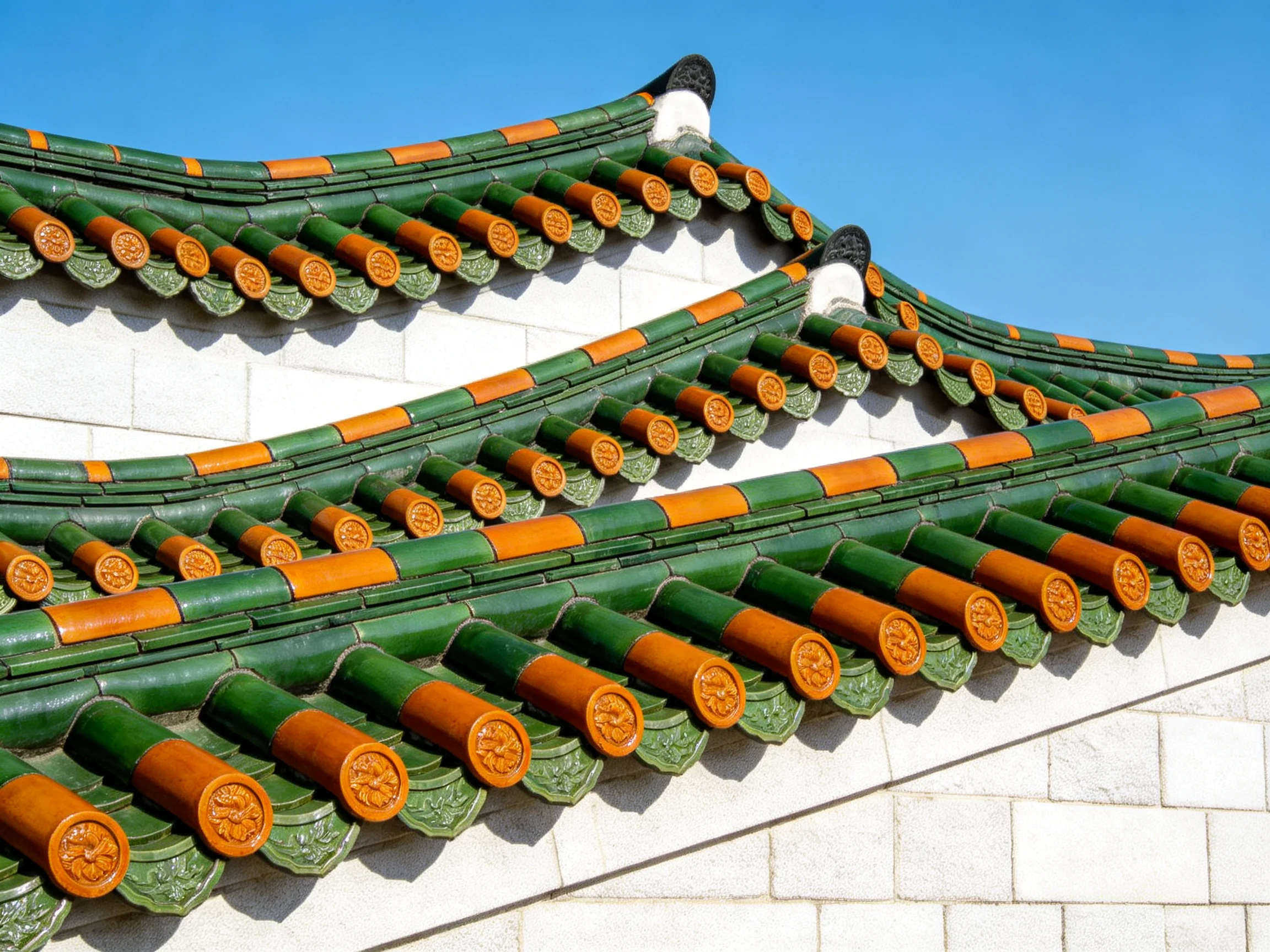 Multi-layered traditional roof with green and orange tiles against clear blue sky